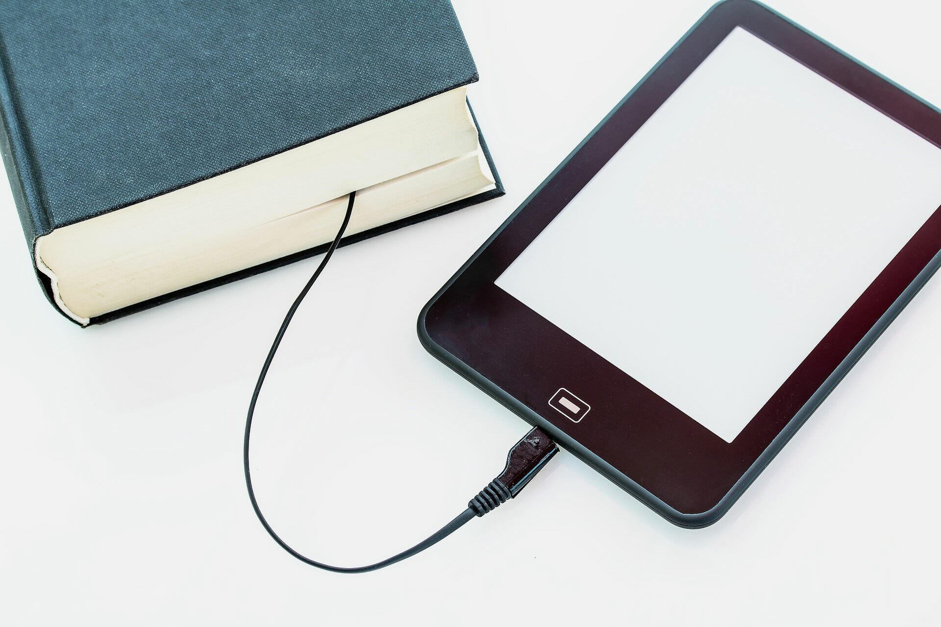 E-Book, das über ein Kabel symbolisch mit einem Buch verbunden ist.