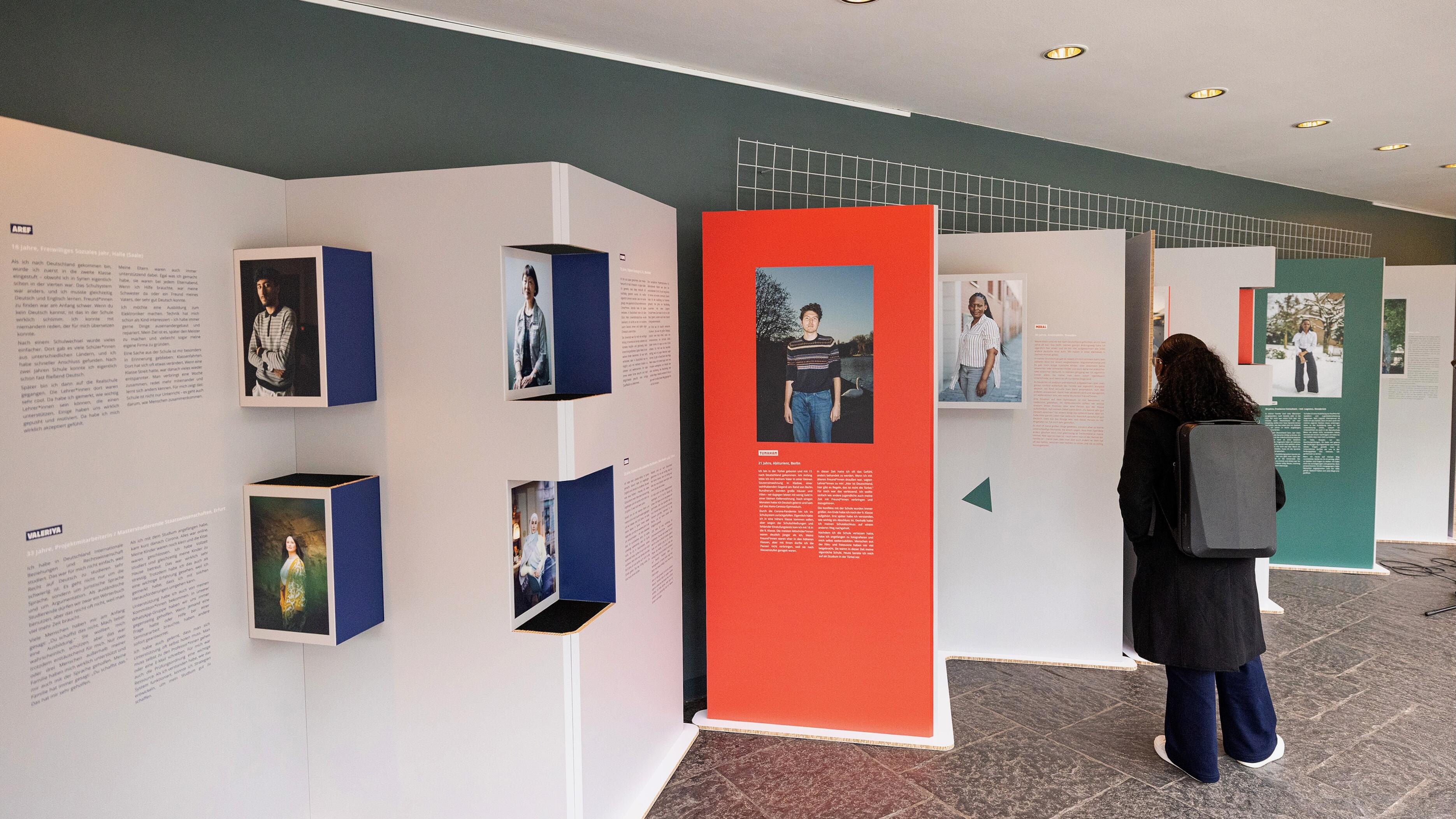 Eine Besucherin schaut sich verschiedene Ausstellungstafeln der Wanderausstellung "Bildungswege in der Migrationsgesellschaft" an.