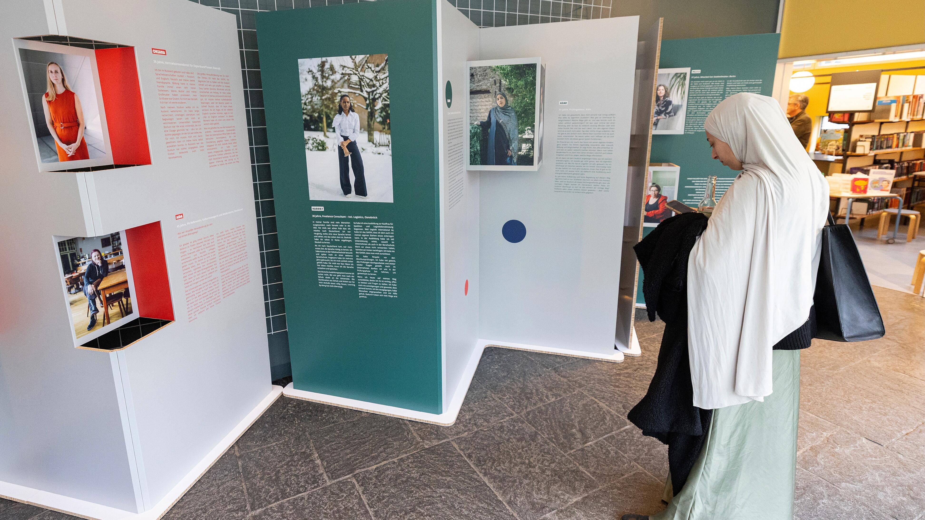 Eine junge Dame macht ein Foto von einer Ausstellungstafel der Wanderausstellung "Bildungswege in der Migrationsgesellschaft".