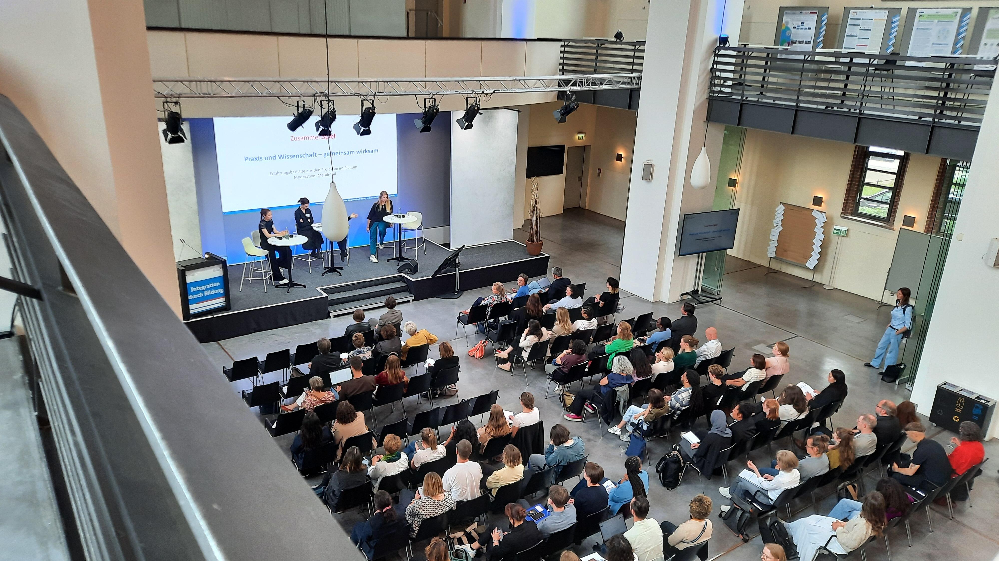 Vogelperspektive auf das Plenum der Vernetzungstagung des Metavorhabens MetaIntBil im Umweltforum Berlin mit sitzenden Teilnehmenden im Veranstaltungsraum.