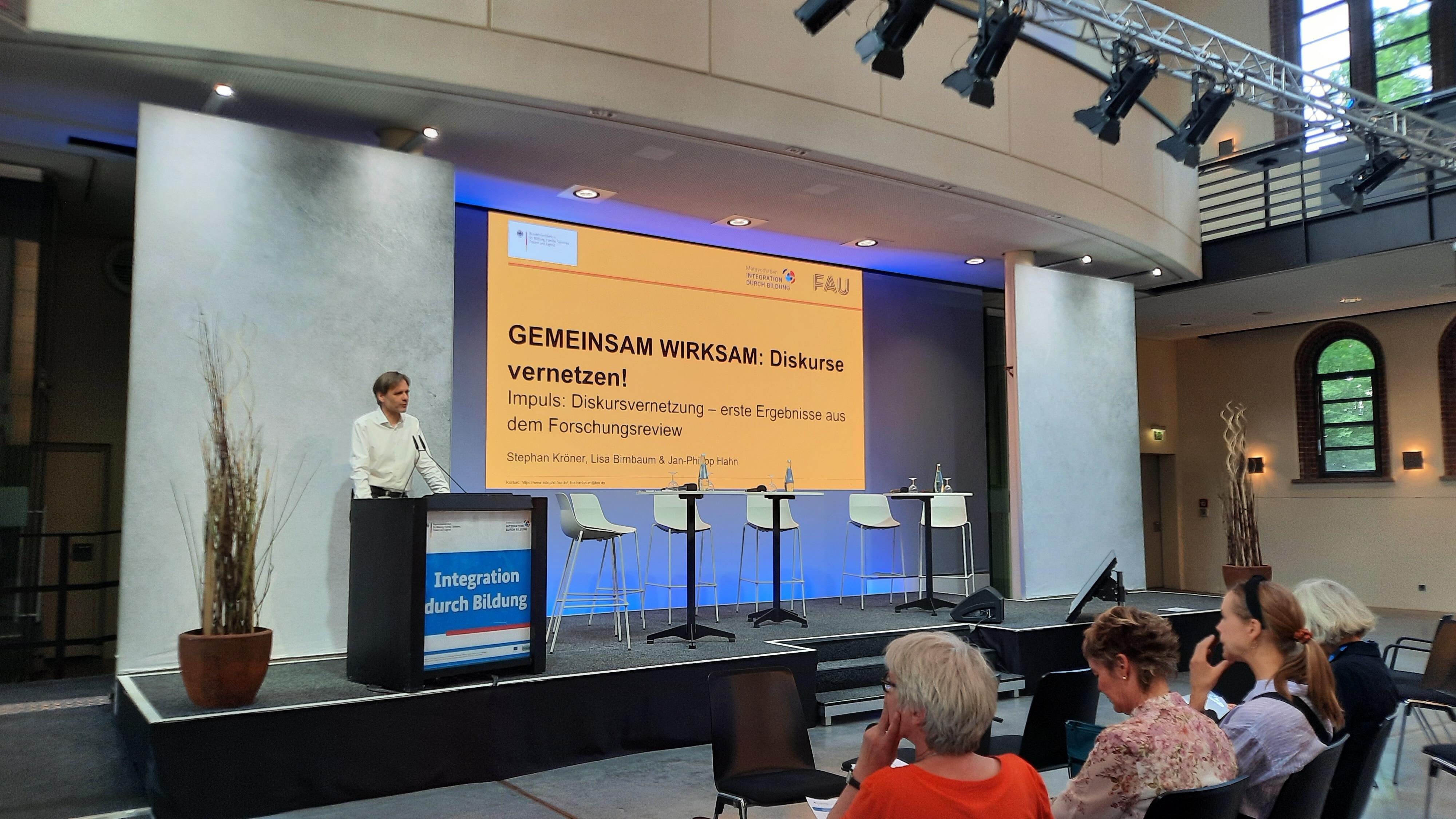 Prof. Dr. Stephan Kröner spricht auf der Bühne der Vernetzungstagung des Metavorhabens MetaIntBil.