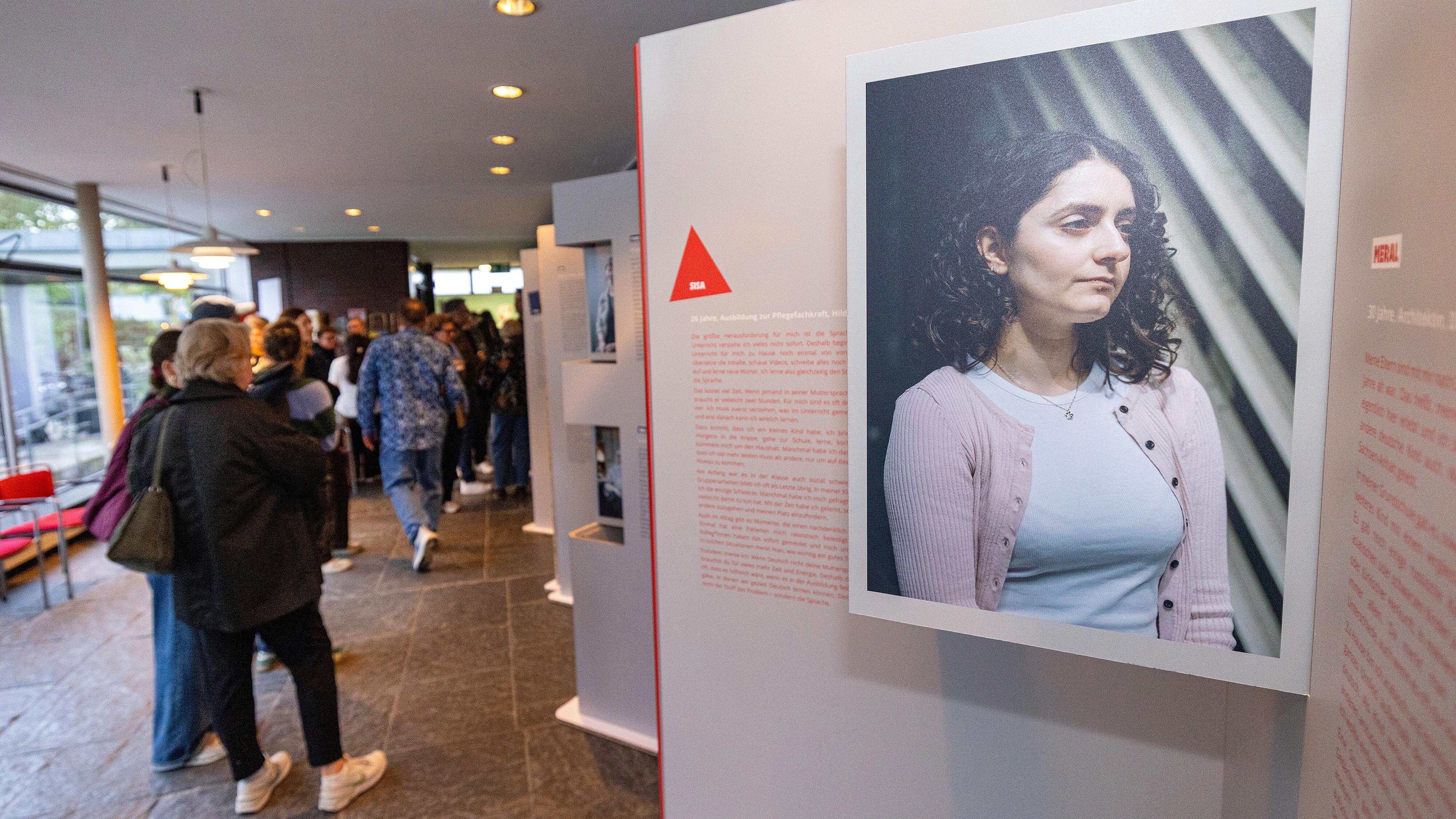 Besucher und Besucherinnen schauen sich Ausstellungstafeln der Wanderausstellung "Bildungswege in der Migrationsgesellschaft" an.