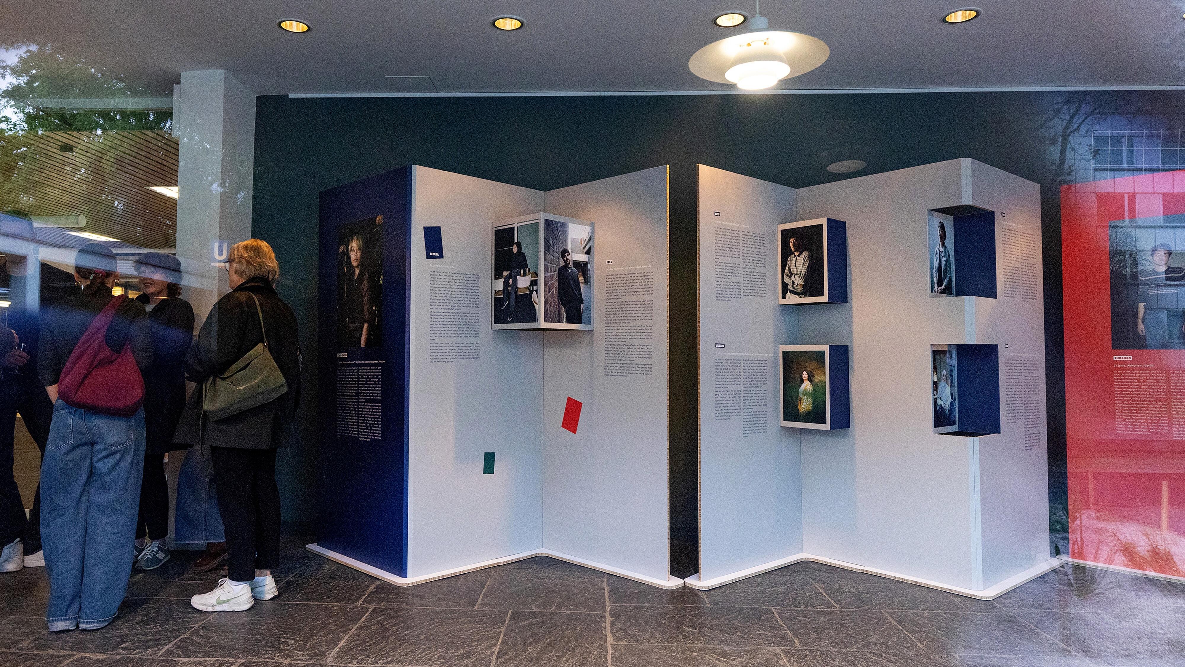 Besucher und Besucherinnen tauschen sich bei der Wanderausstellung "Bildungswege in der Migrationsgesellschaft" aus.