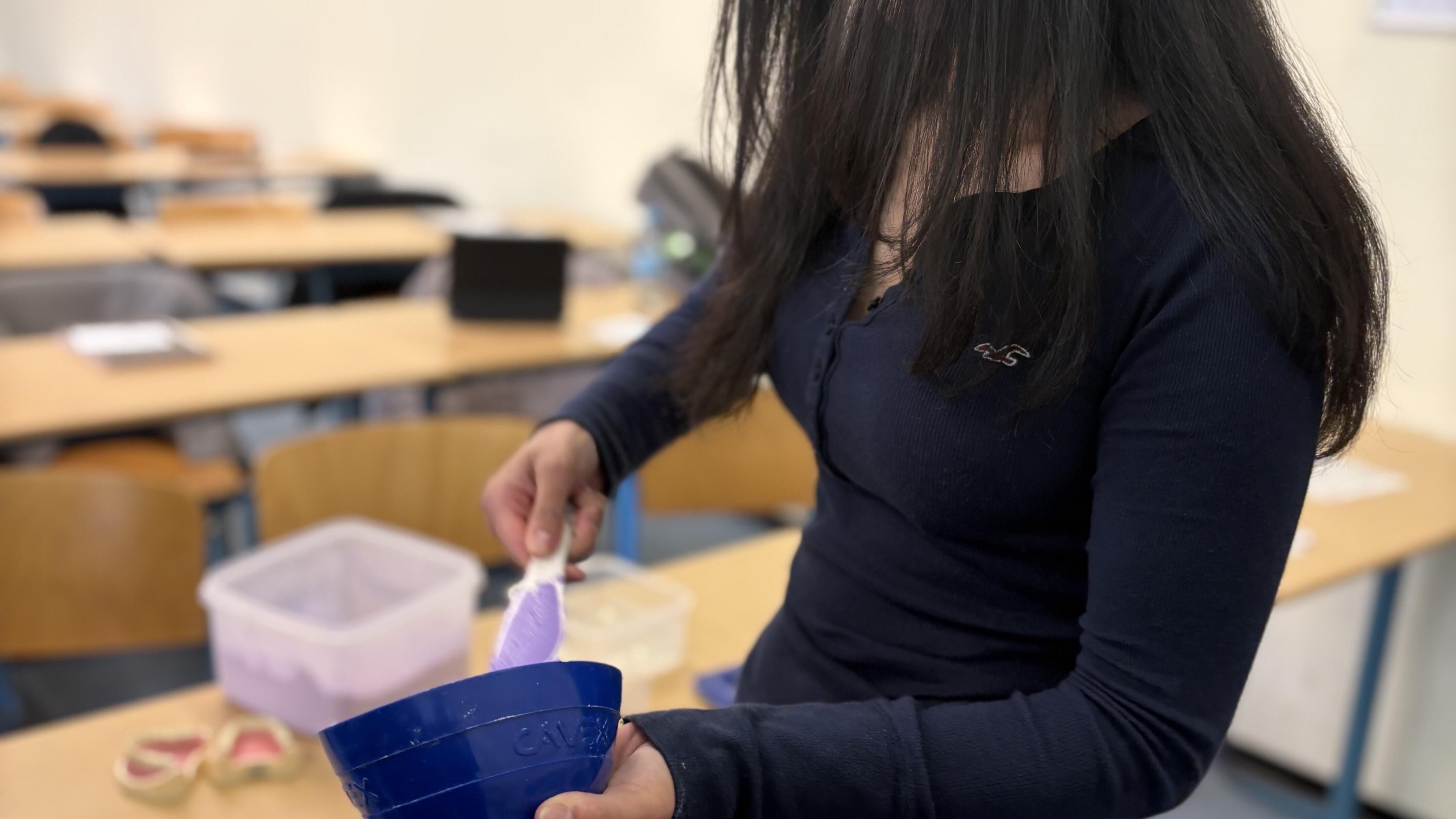 Eine junge Studentin mischt Gips für die Herstellung von Zahnabdrücken in einer Schüssel.