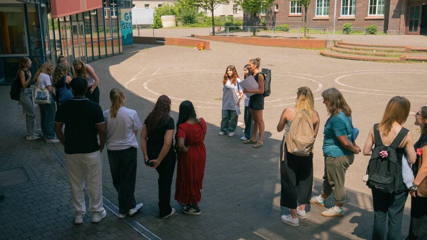 Mehrere Jugendliche der Mädchen-AG Inside Marxloh stehen gemeinsam auf einem Platz und unterhalten sich.