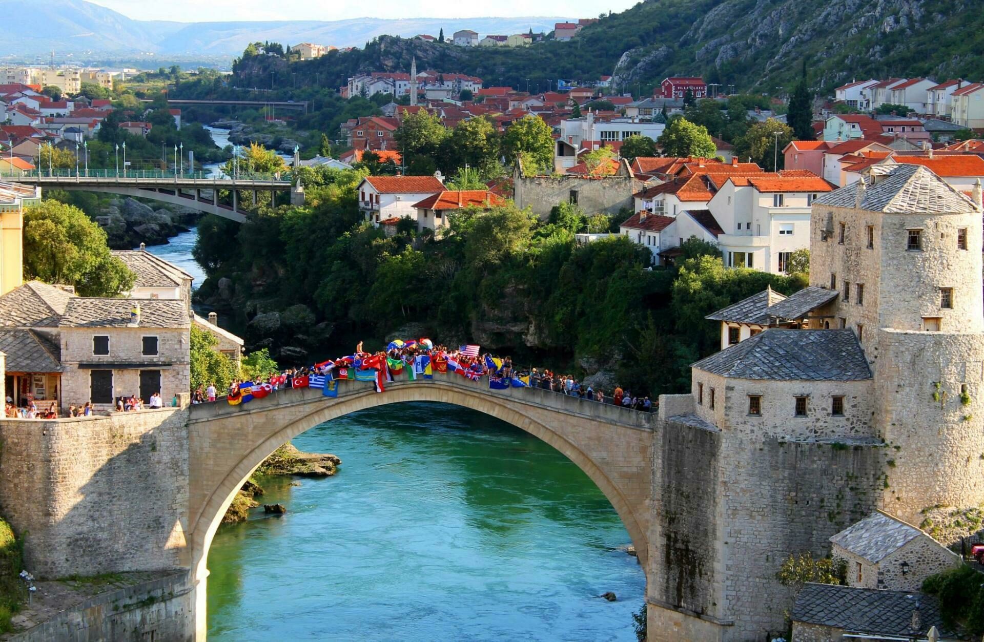 Schülerinnen und Schüler des United World Colleges stehen gemeinsam auf der Mostar-Brücke in Mostar, Bosnien-Herzegowina.