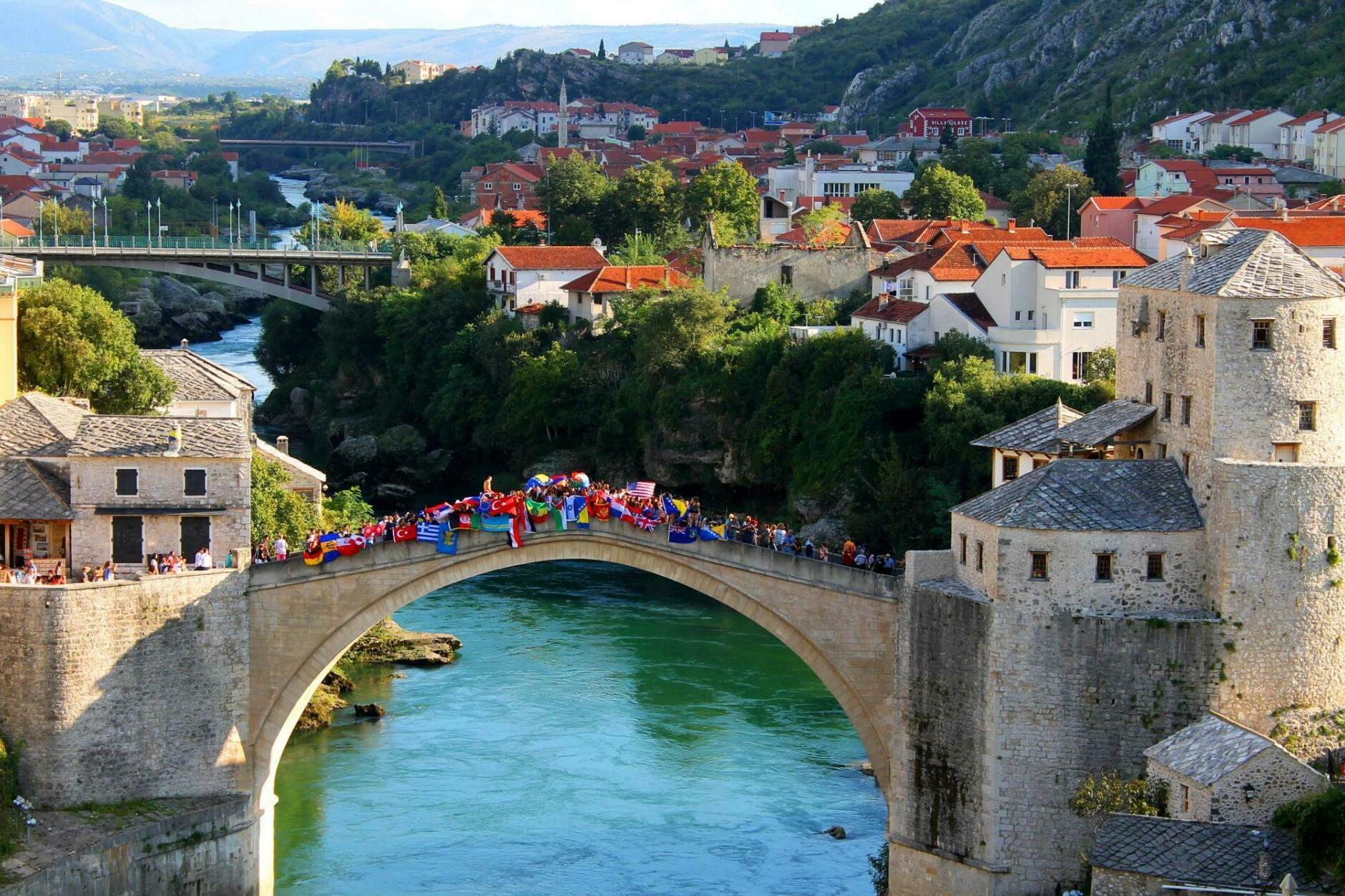 Schülerinnen und Schüler des United World Colleges stehen gemeinsam auf der Mostar-Brücke in Mostar, Bosnien-Herzegowina.