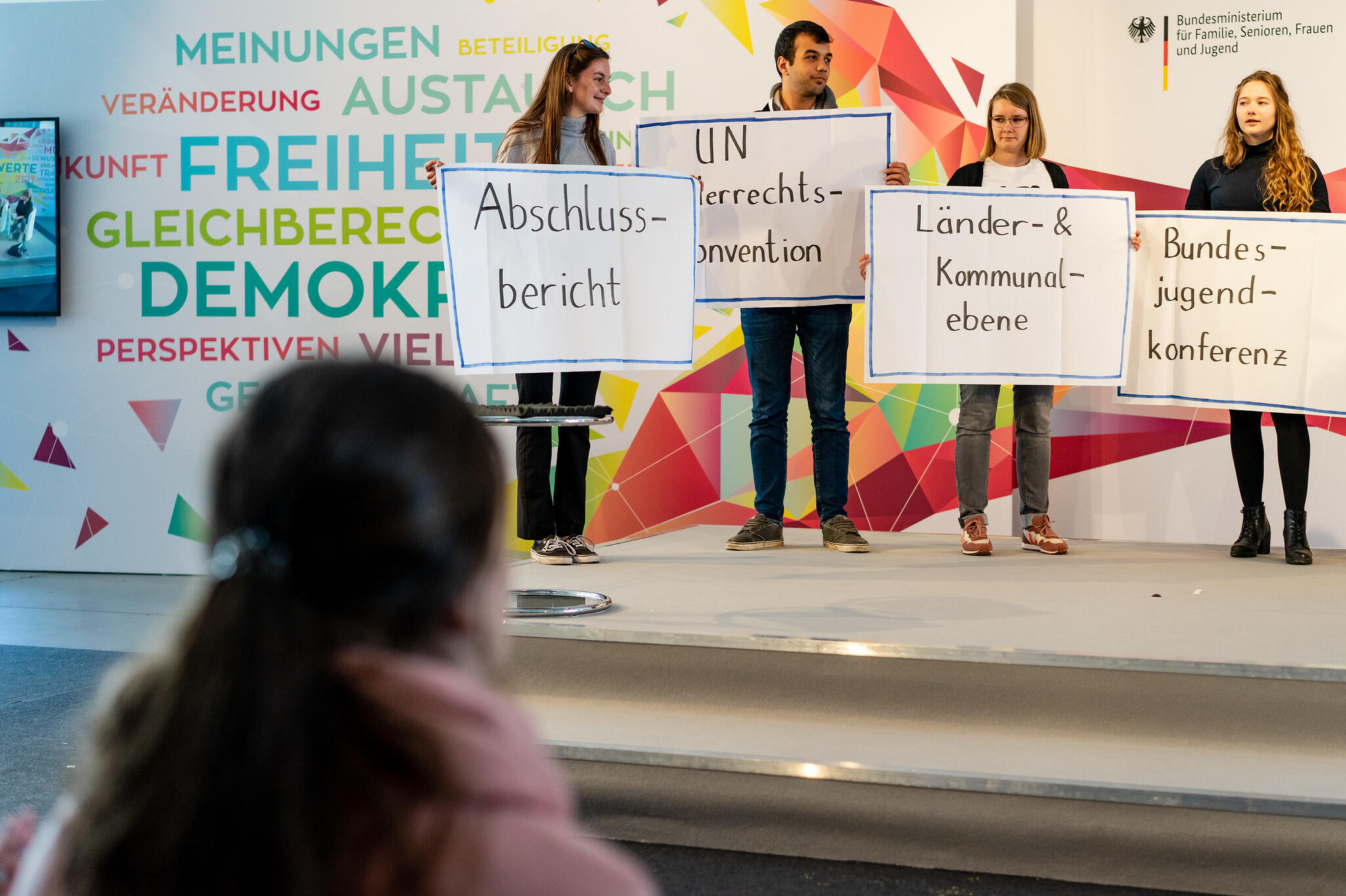 4 Personen auf der Bühne mit Schildern in den Händen