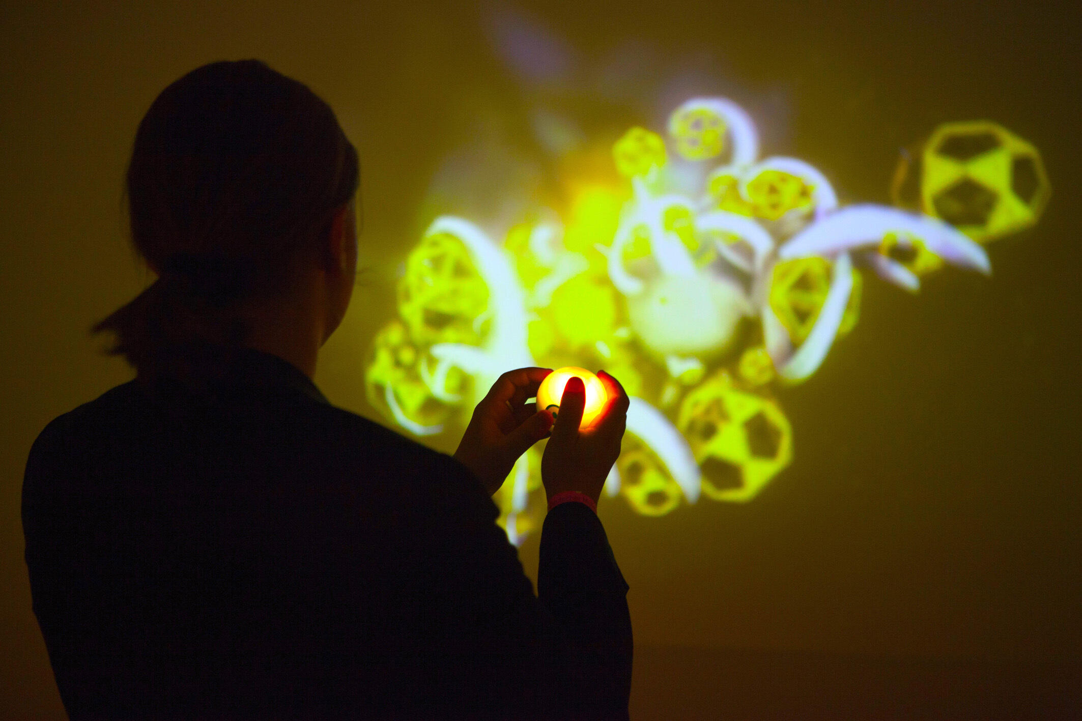 Mensch spielt mit Lichtprojektion an einer Wand.