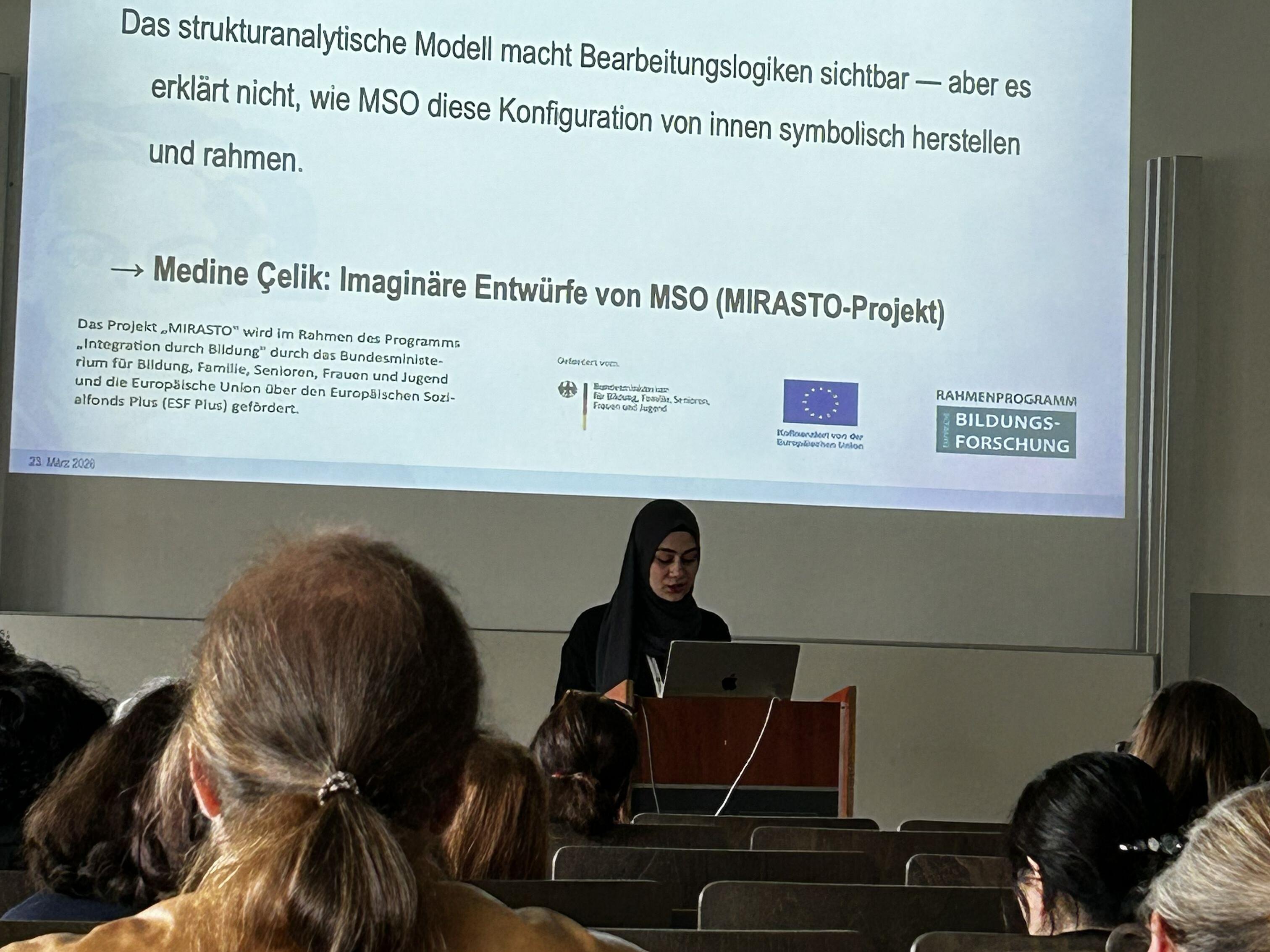 Medine Celik hält eine Präsentation in einem Saal vor Publikum.