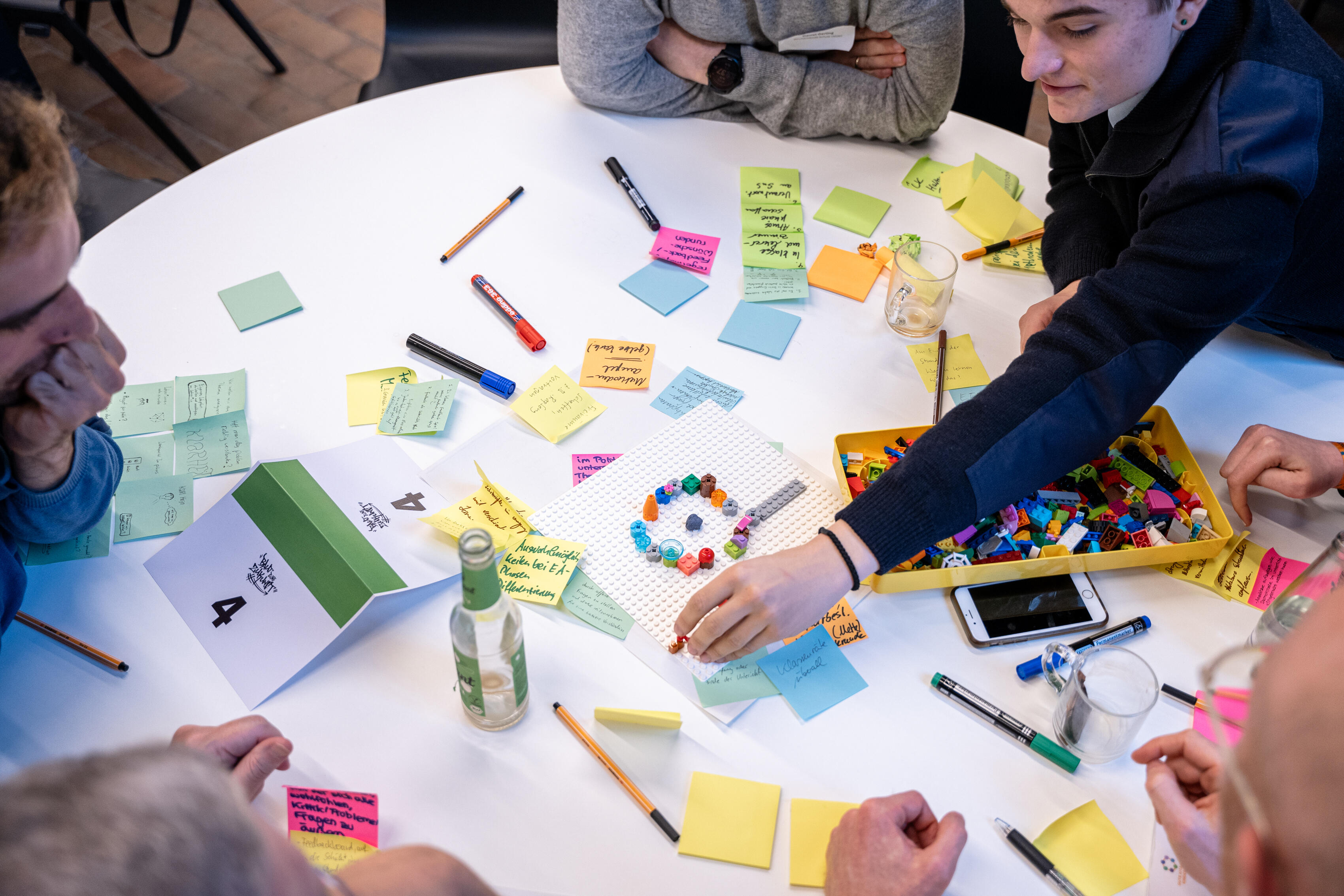 Bild aus der Bildungswerkstatt der Organisation Baut Eure Zukunft: Teilnehmende während eines Seminars, die um einen runden Tisch sitzen.