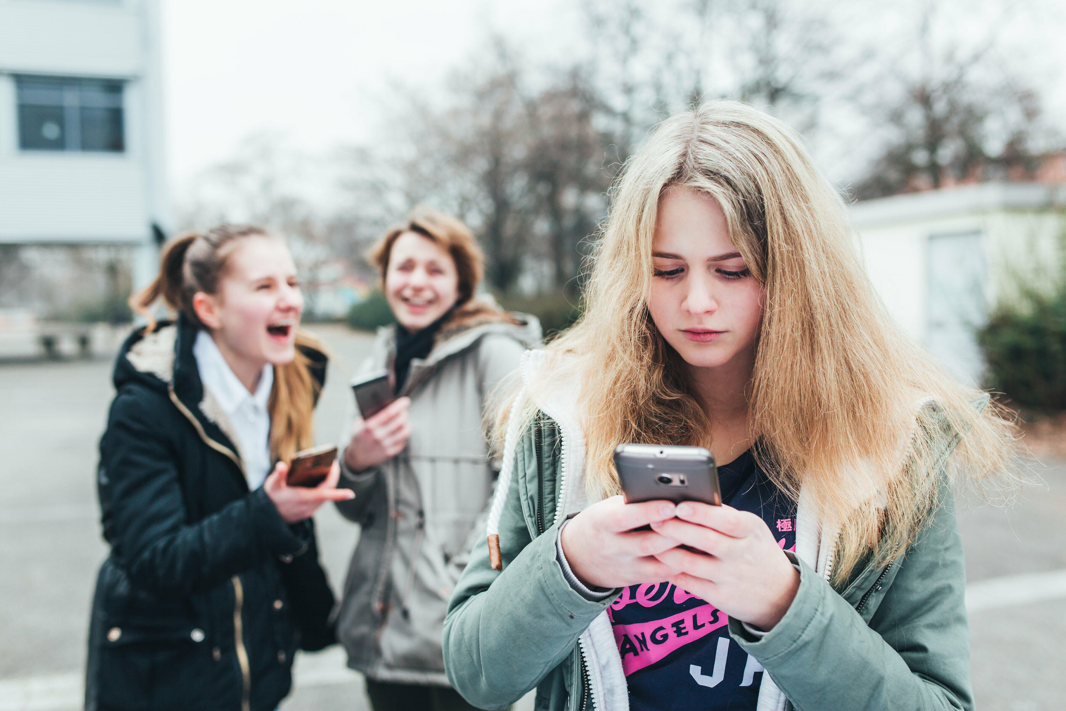 2 Mädchen lästern über ein 3. Mädchen am Handy