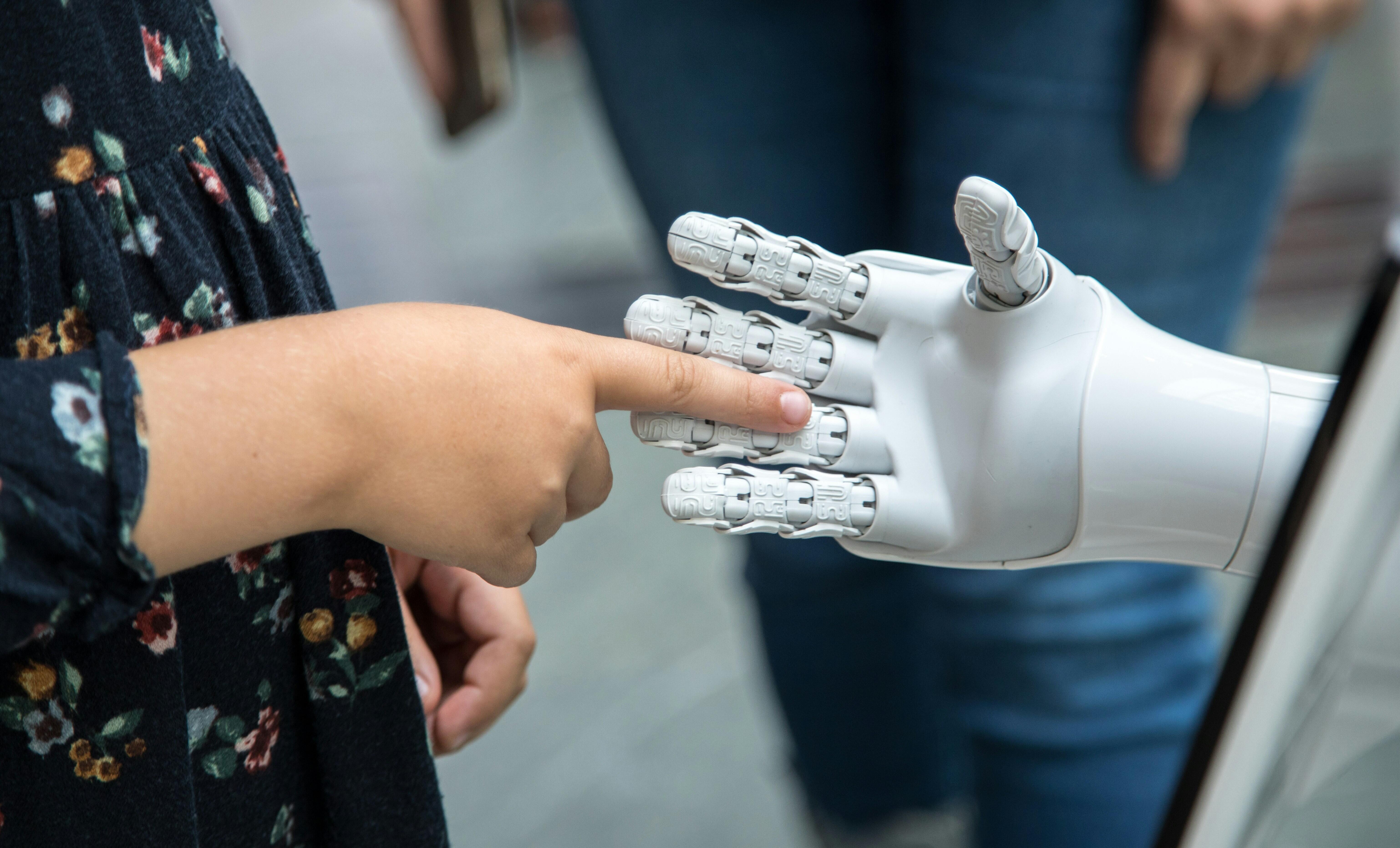 Kinderhand berührt Roboterhand