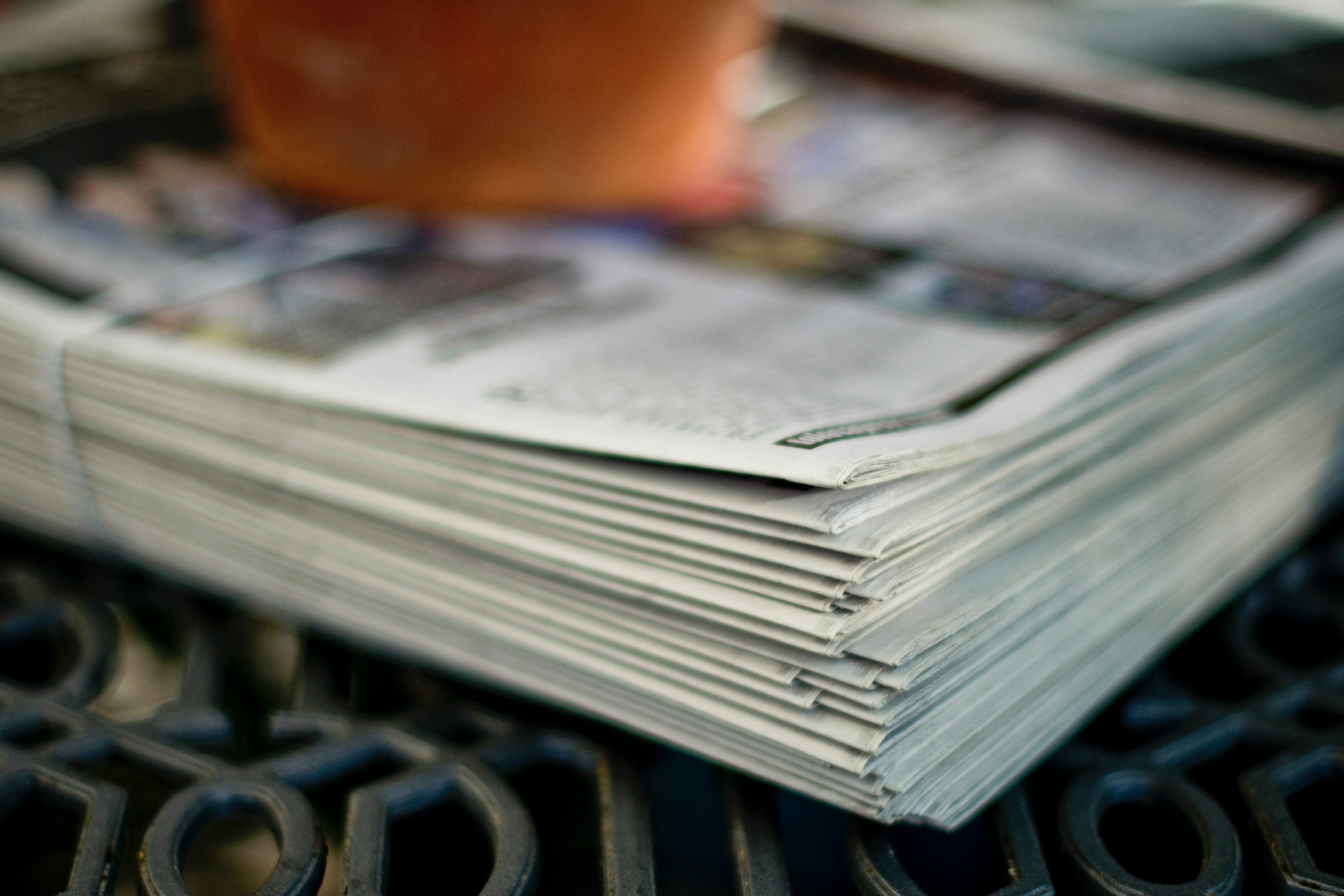 Ein Stapel Zeitungen, die zusammengelegt auf einem Rost liegen.