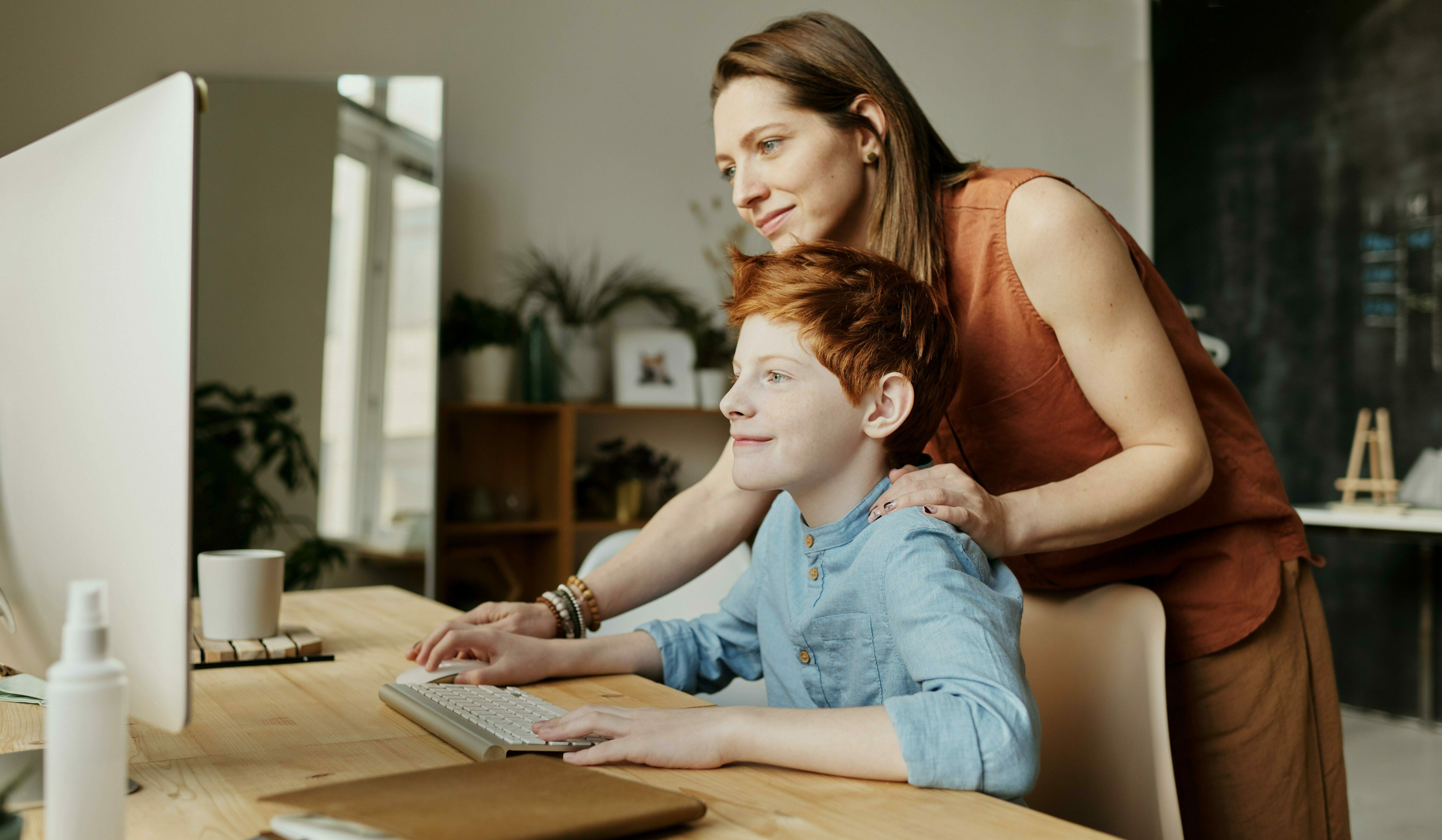 Mutter unterstützt Jungen beim digitalen Lernen.