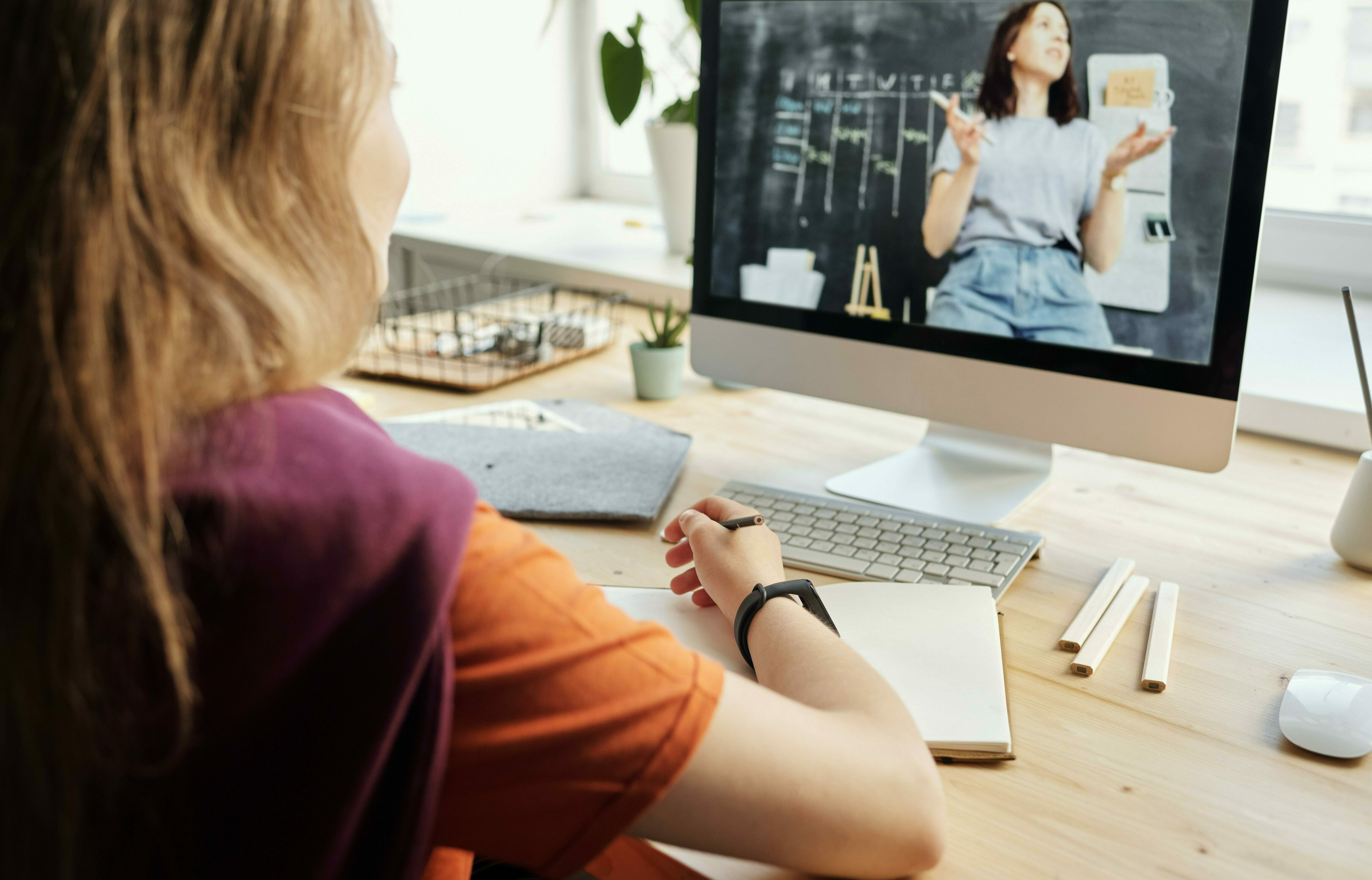 Mädchen sitzt vor Laptop und lernt online.