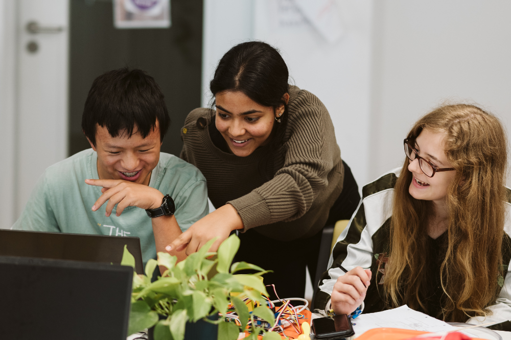 Drei Jugendliche, die vor einem PC sitzen und Spaß haben.