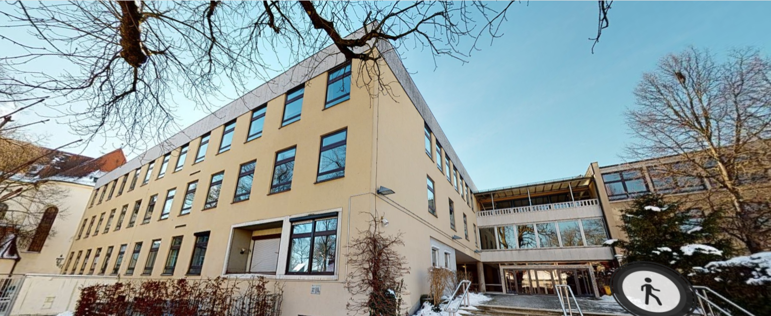 Vom Pausenhof aus gesehen zeigt das Bild den Haupteingang der Schule sowie das markant im Bauhausstil gehaltenen Hauptgebäude aus dem 60er Jahren.