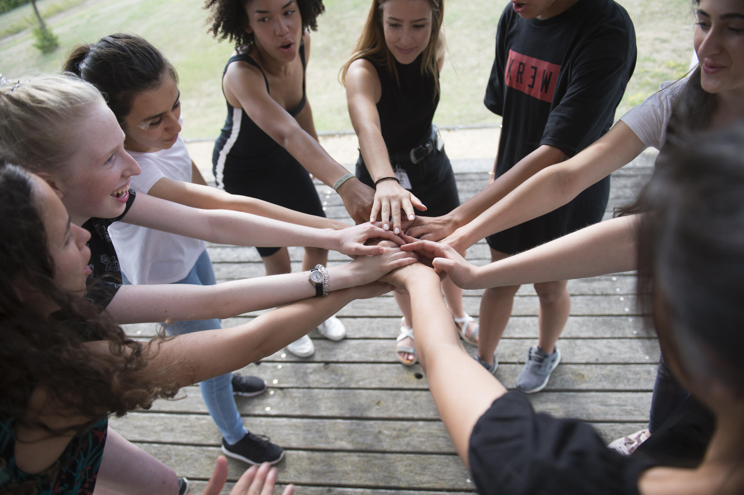 Junge Menschen stehen im Kreis und halten jeweils eine Hand in die Mitte als Zeichen ihrer Verbundenheit