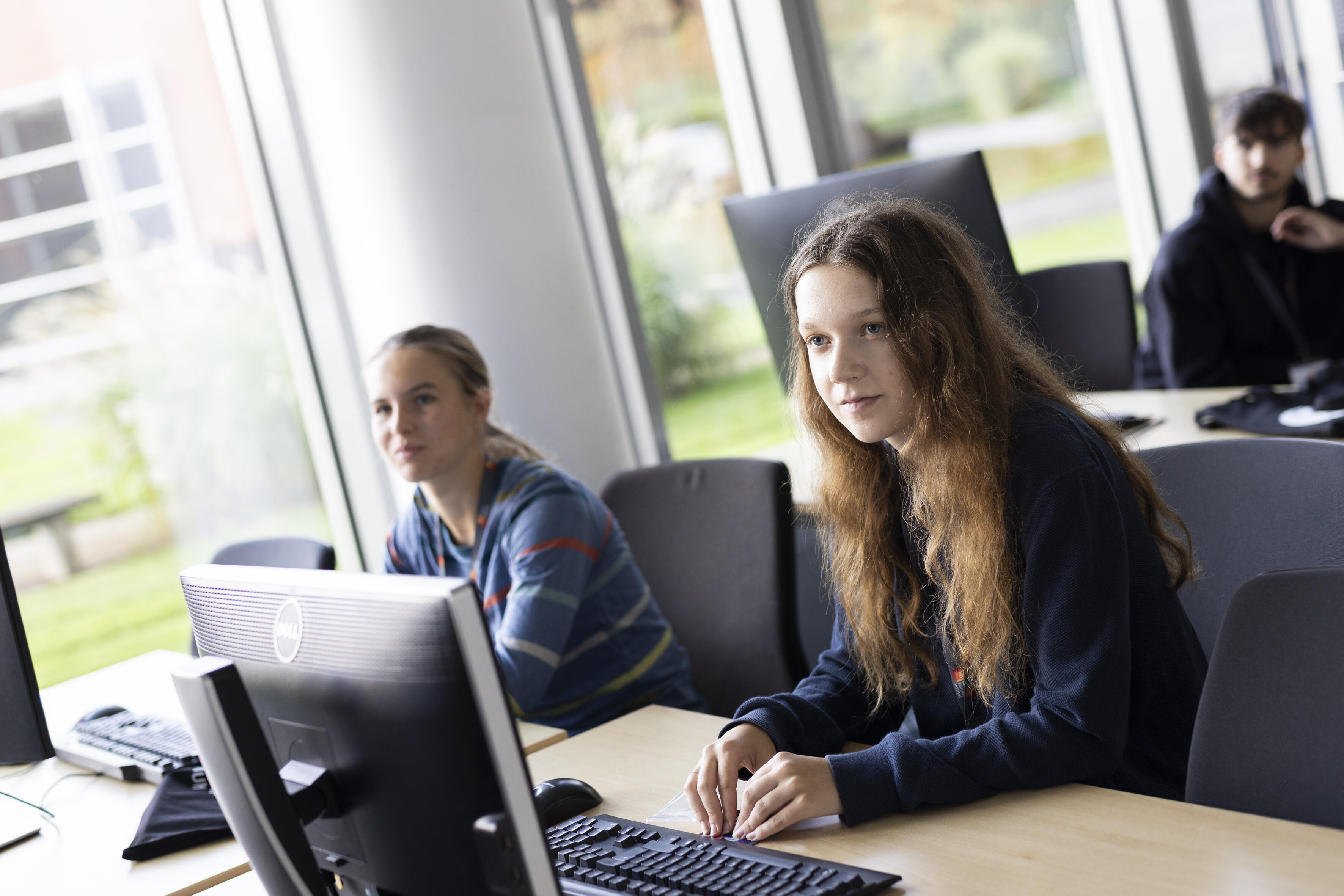 zwei Schülerinnen sitzen an Computern