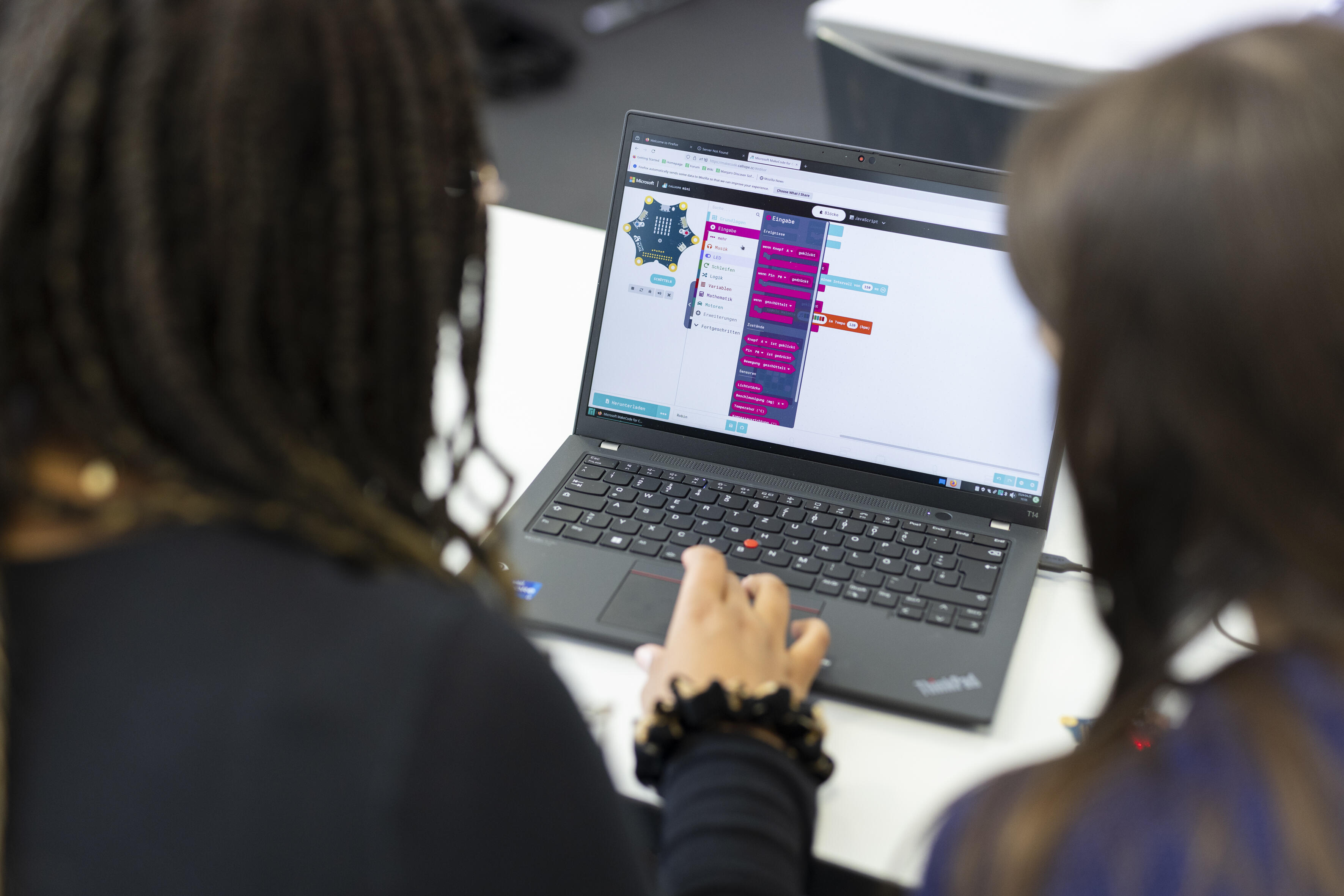 zwei Mädchen sitzen vor einem Laptop