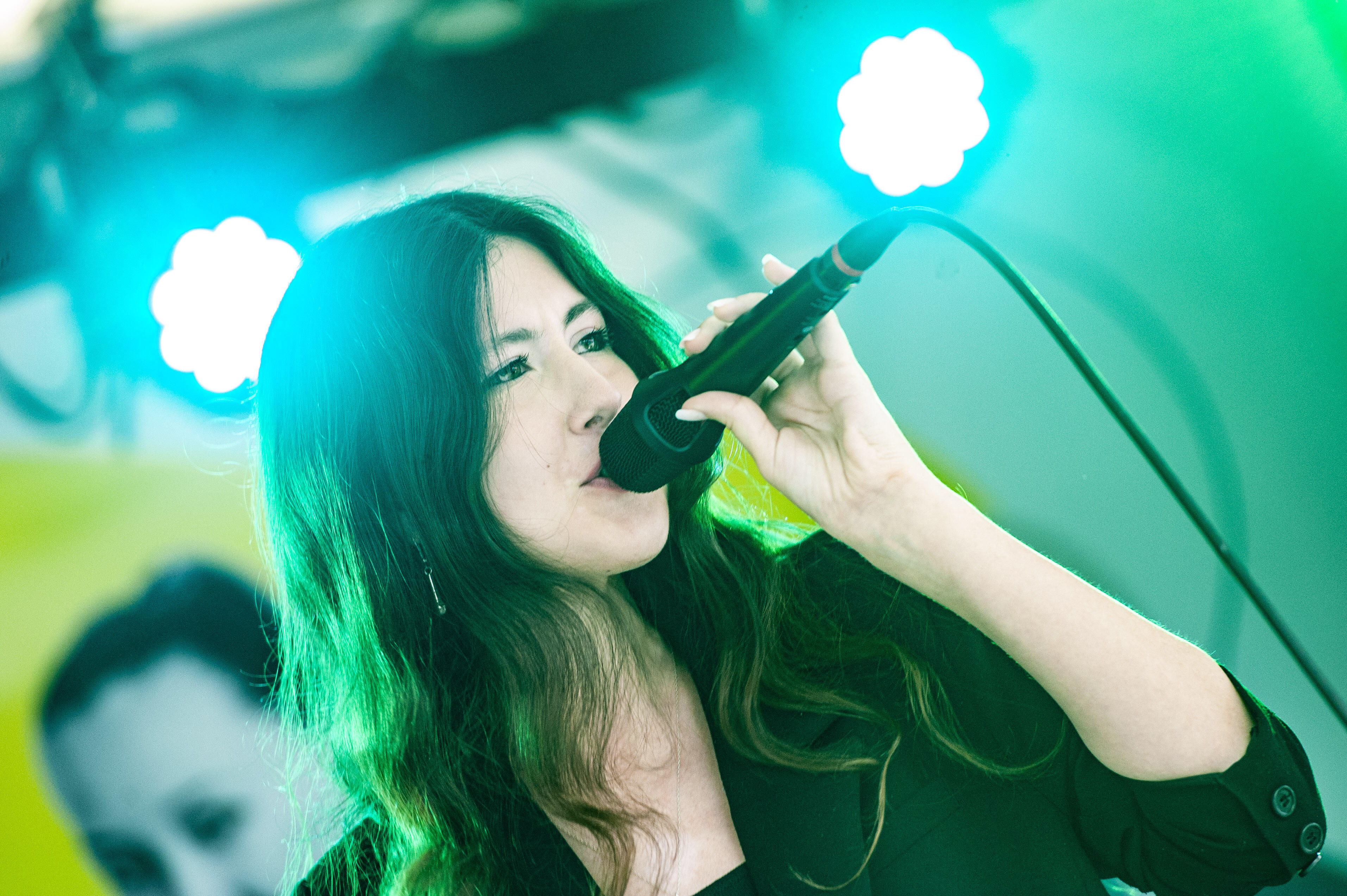 Das Bild zeigte eine Gewinnerin des Song Contests, die ihren Song auf einer Bühne singt. Sie hält ein Mikrofon in der Hand. Im Hintergrund leuchten Scheinwerfer.