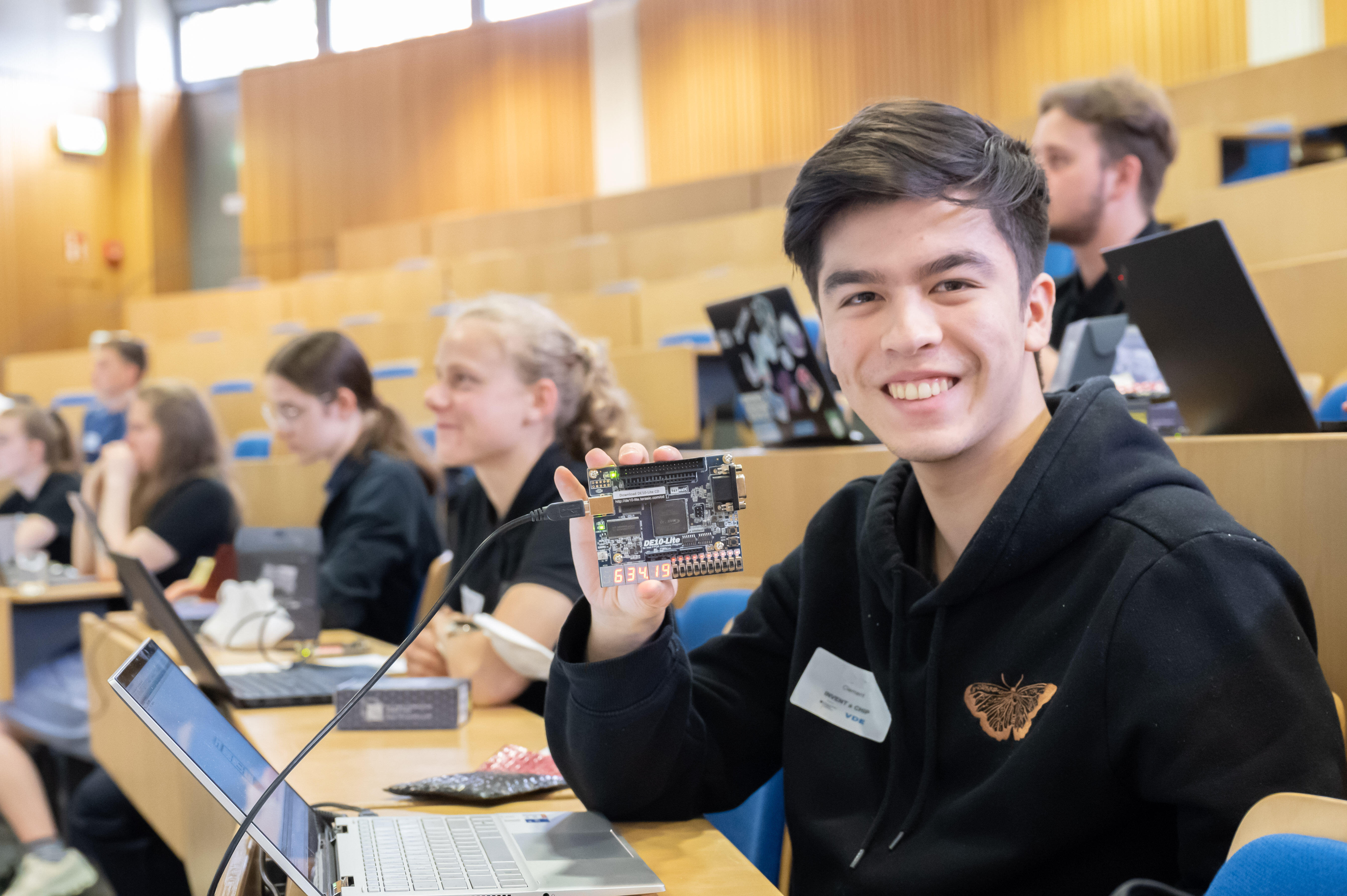 Ein Schüler zeigt das technische Entwicklungs-Board (FPGA) im Rahmen des IaC-Camps in Hannover.
