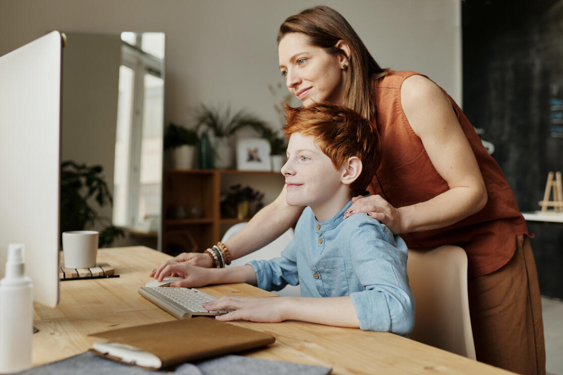 Frau und Junge schauen auf einen Desktop