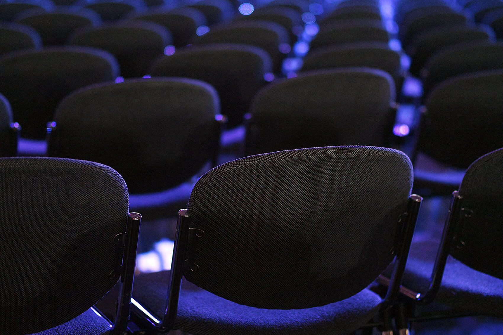 Bestuhlung eines Veranstaltungsraums mit blauem Neonlicht hinterlegt