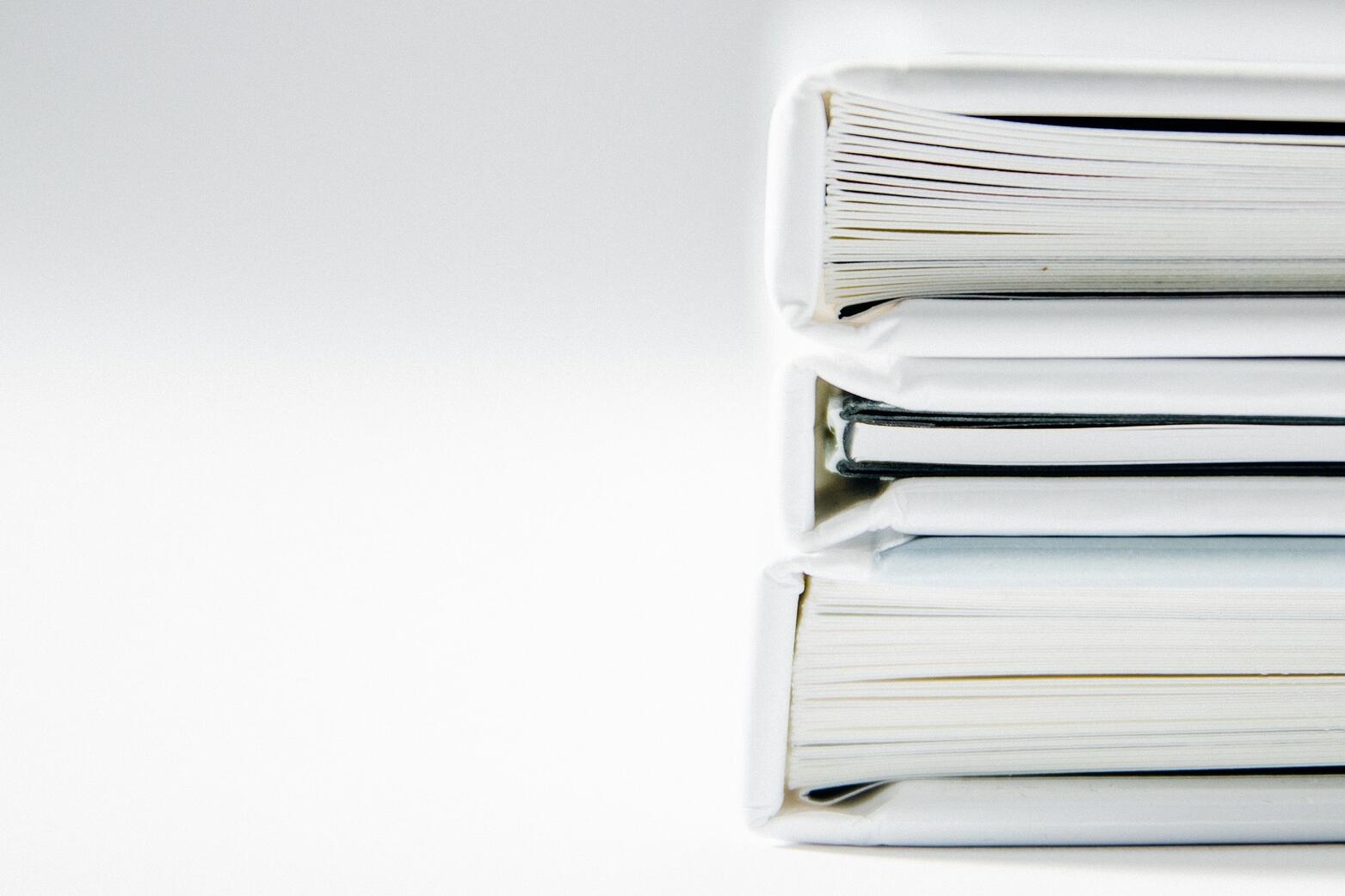 Drei Bücher mit weißem Umschlag, die aufeinander liegen.
