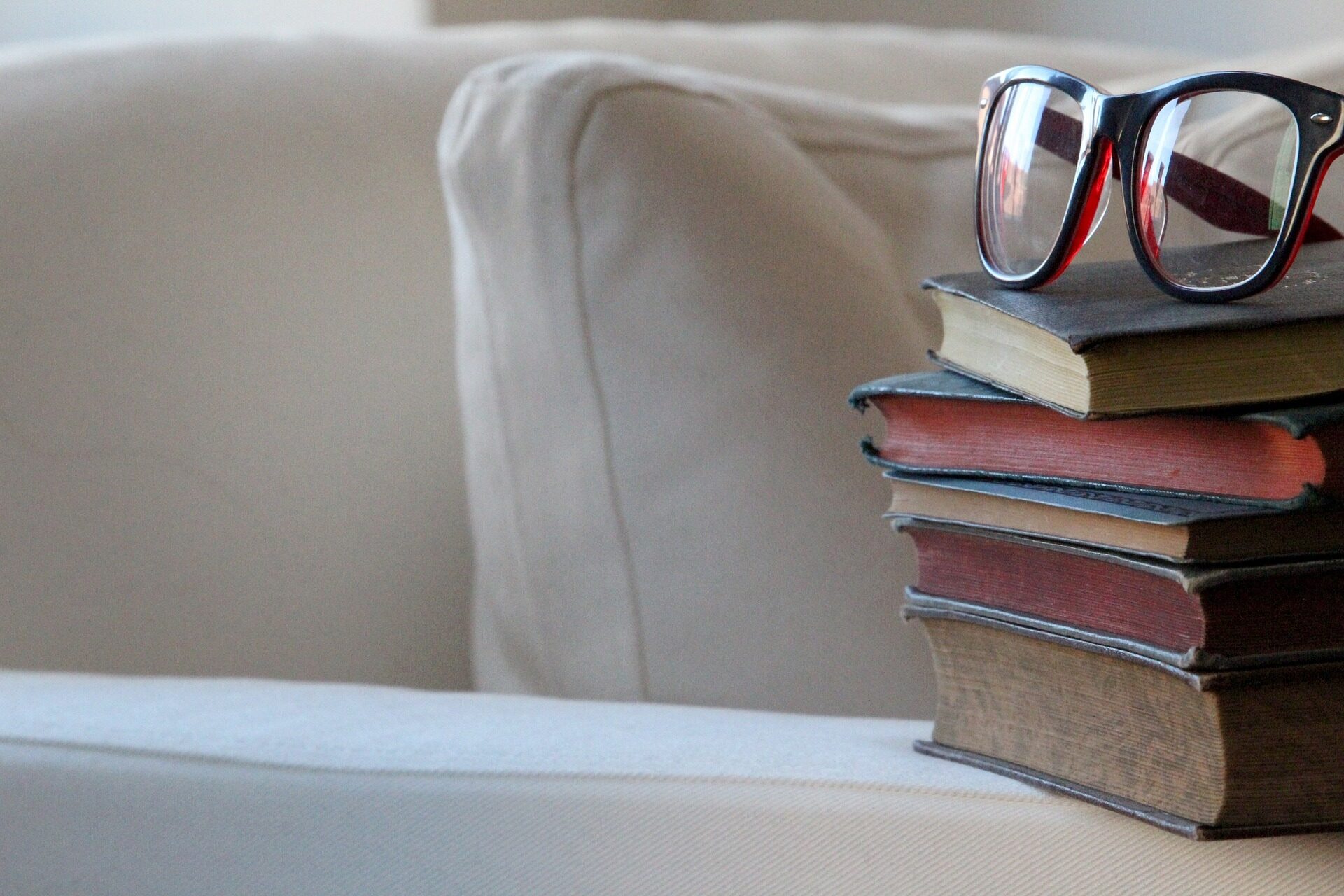 Ein Bücherstapel mit Brille auf einem Sofa