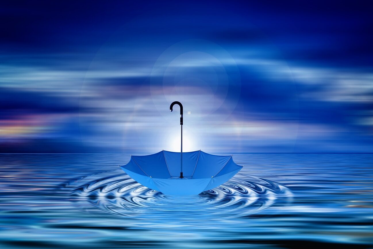 Blaues Wasser vor blauem Horizont und ein blauer Regenschirm, der auf dem Wasser tanzt.