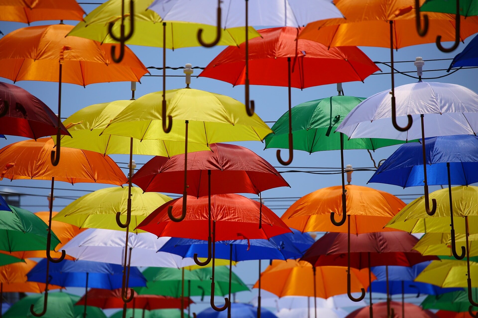 Viele bunte aufgespannte Regenschirme, die am Himmel schweben