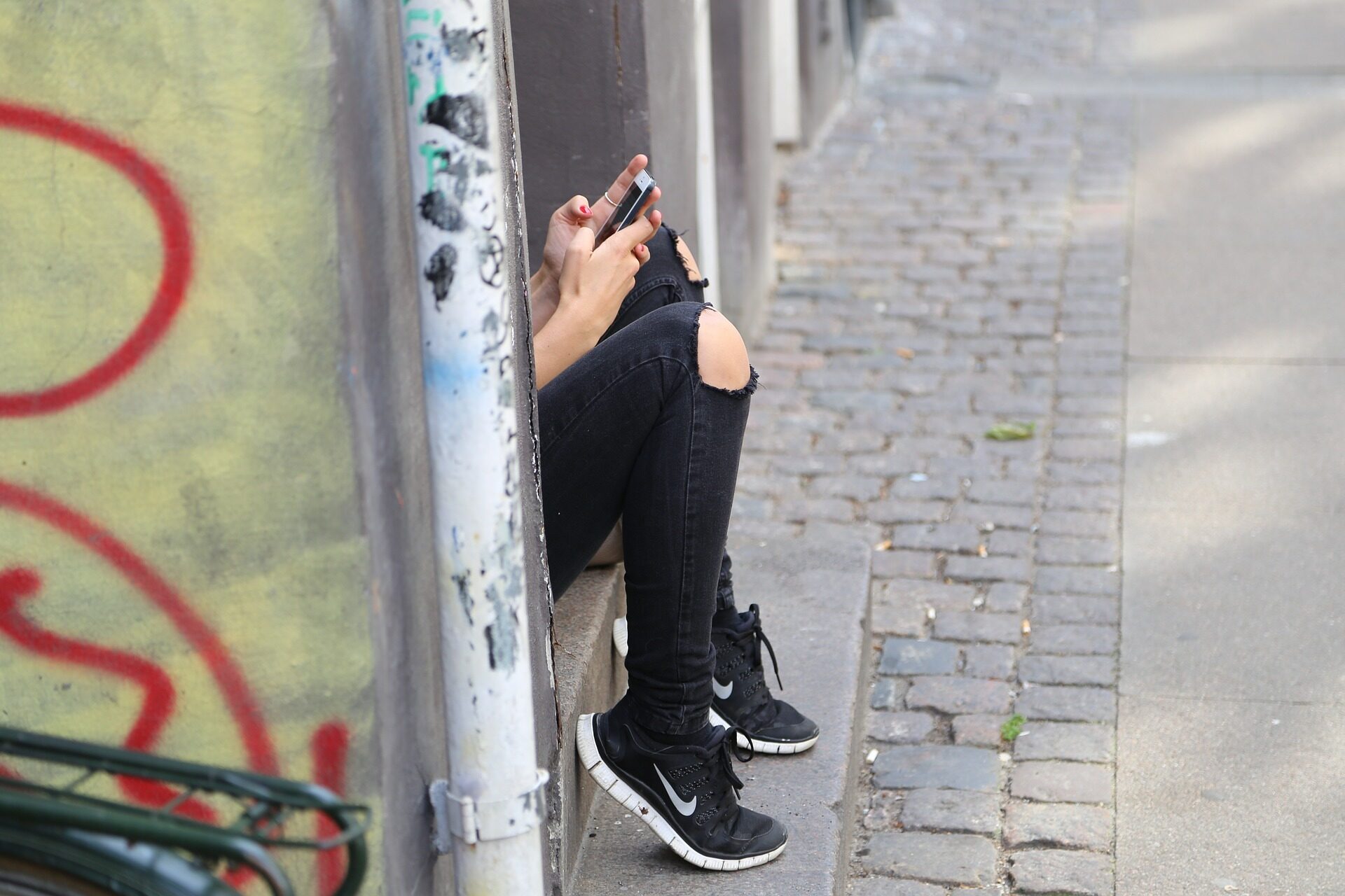 Bild eines Mädchens mit Handy in der Hand beim Schreiben einer SMS oder beim Lesen von Nachrichten