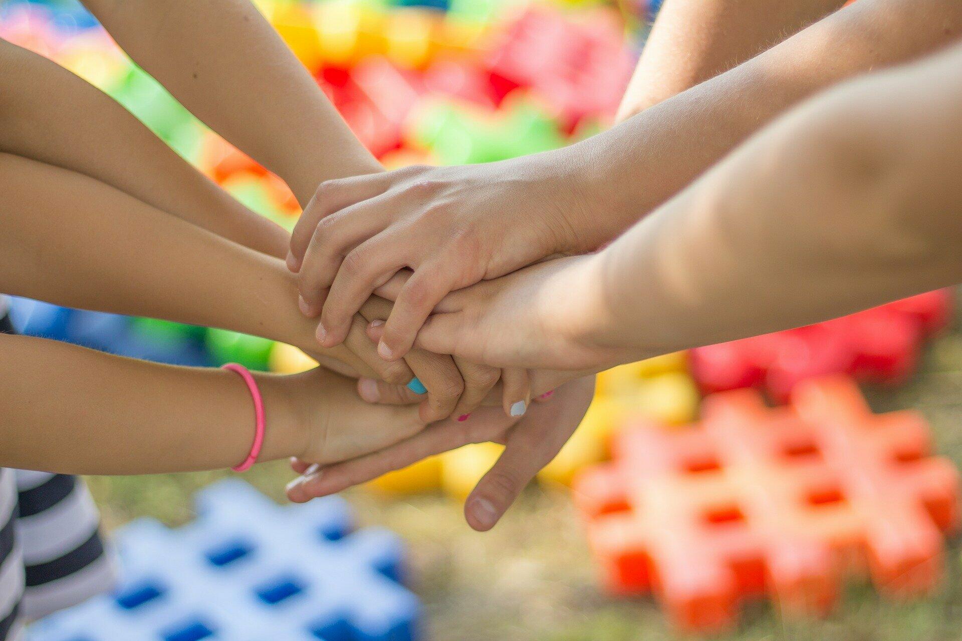 Schülerinnen und Schüler, die ihre Hände ausgestreckt und übereinandergelegt haben.