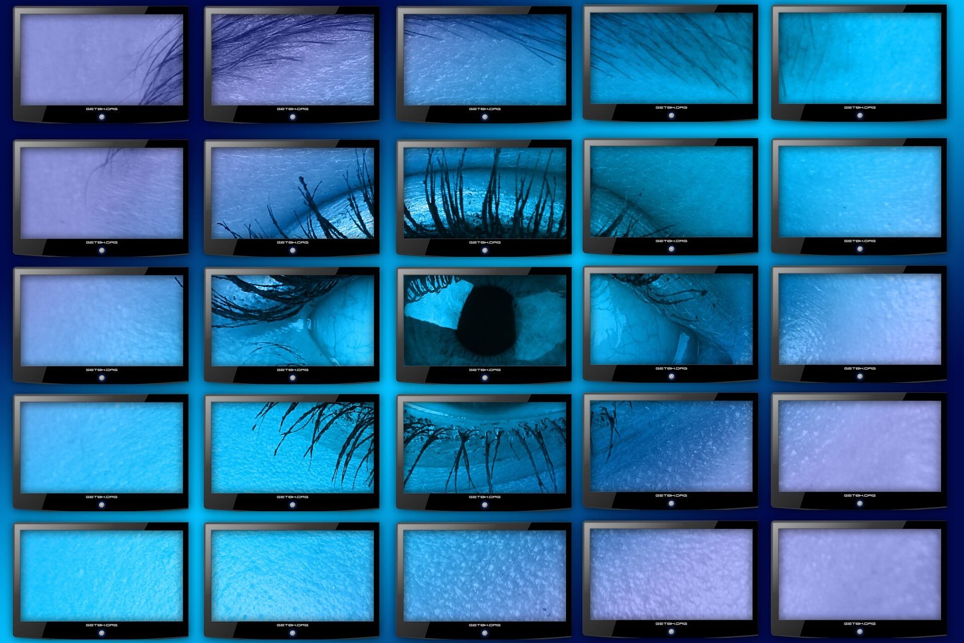 Eine Wand voller Monitore und ein Auge das dahinter betrachtet, was passiert - als Symbol des Bildungsmonitorings.