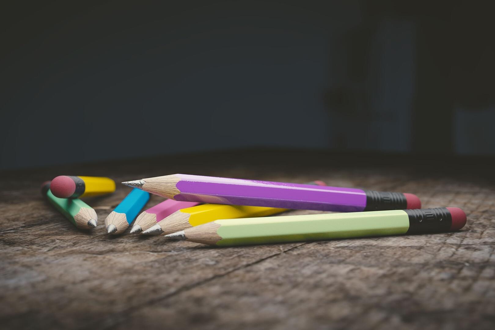 Verschiedene bunte Bleistifte, die auf einem Holztisch liegen