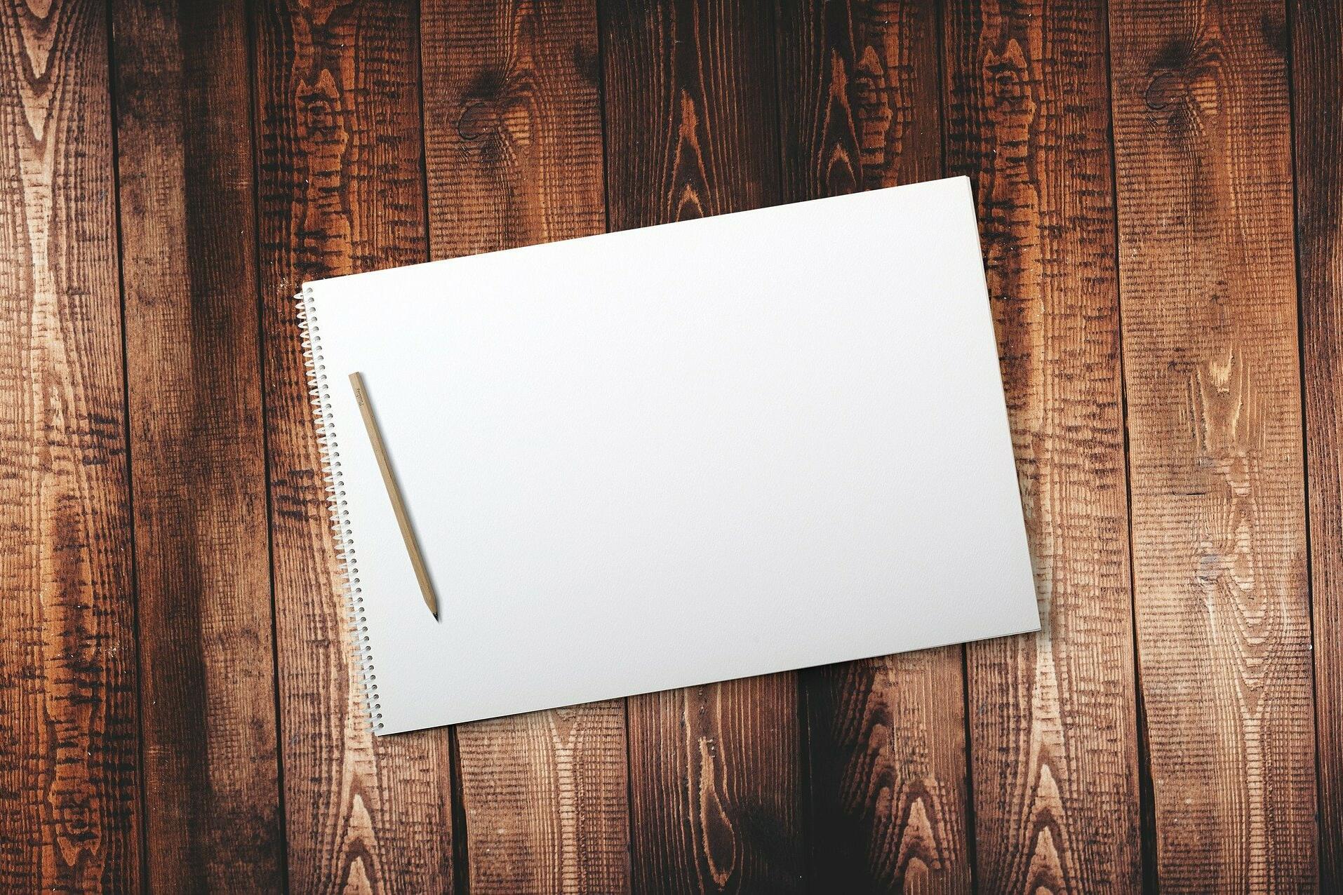 Holztisch mit Papier und Stift darauf.