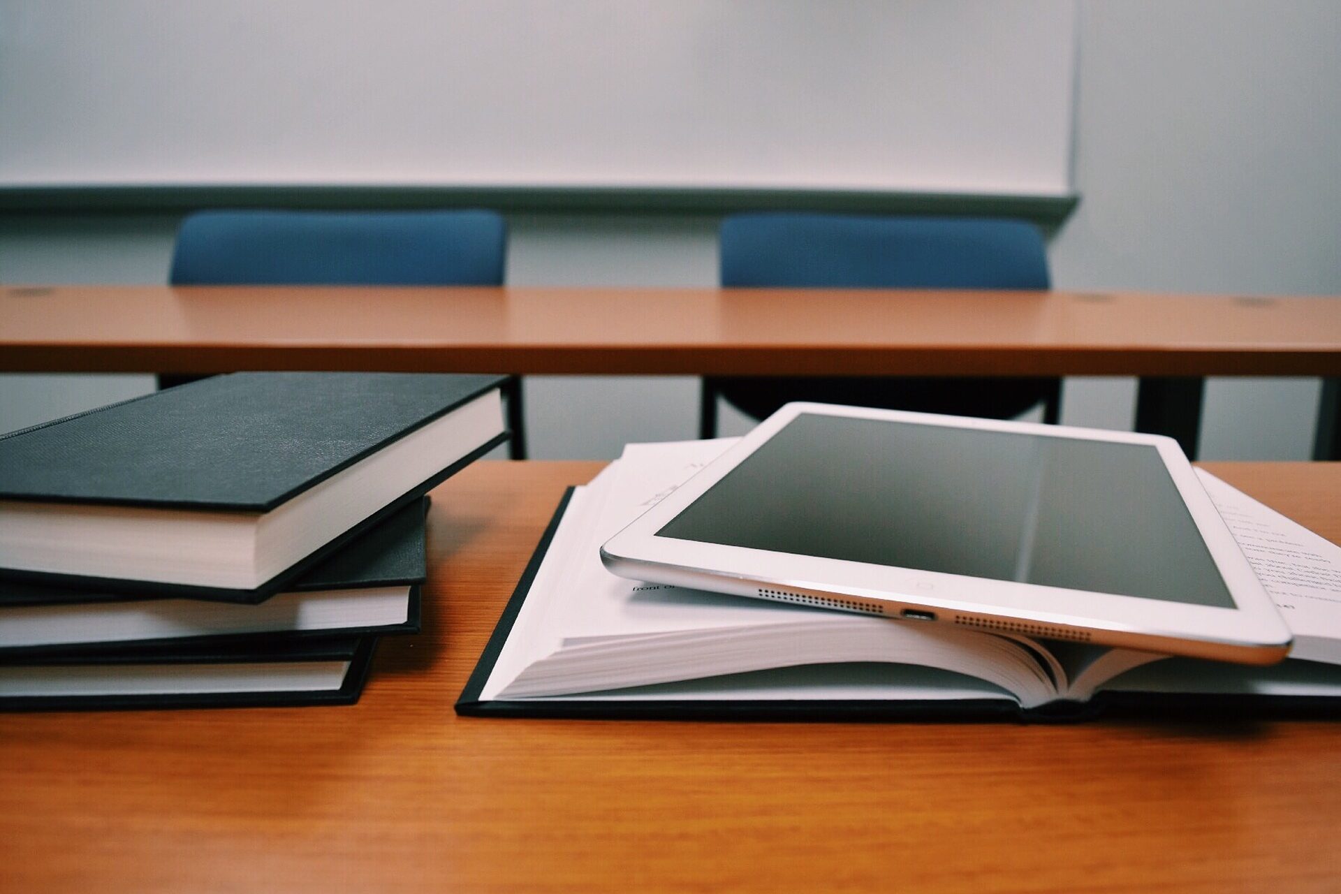 Bücher und ein Tablet auf einer Schulbank zur Veranschaulichung von Schulbildung