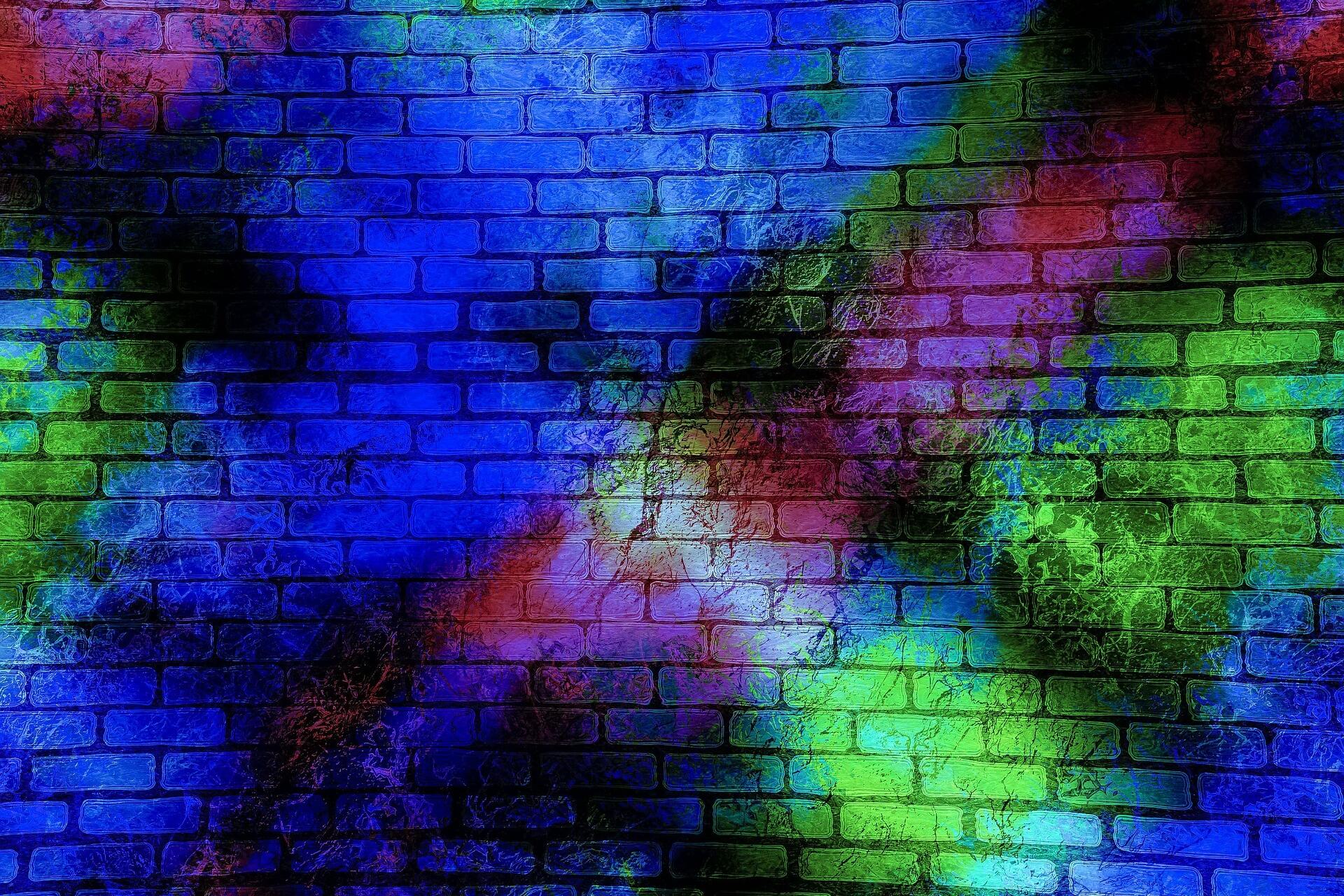Eine Hauswand besprayt mit blauen, grünen und lila Farben