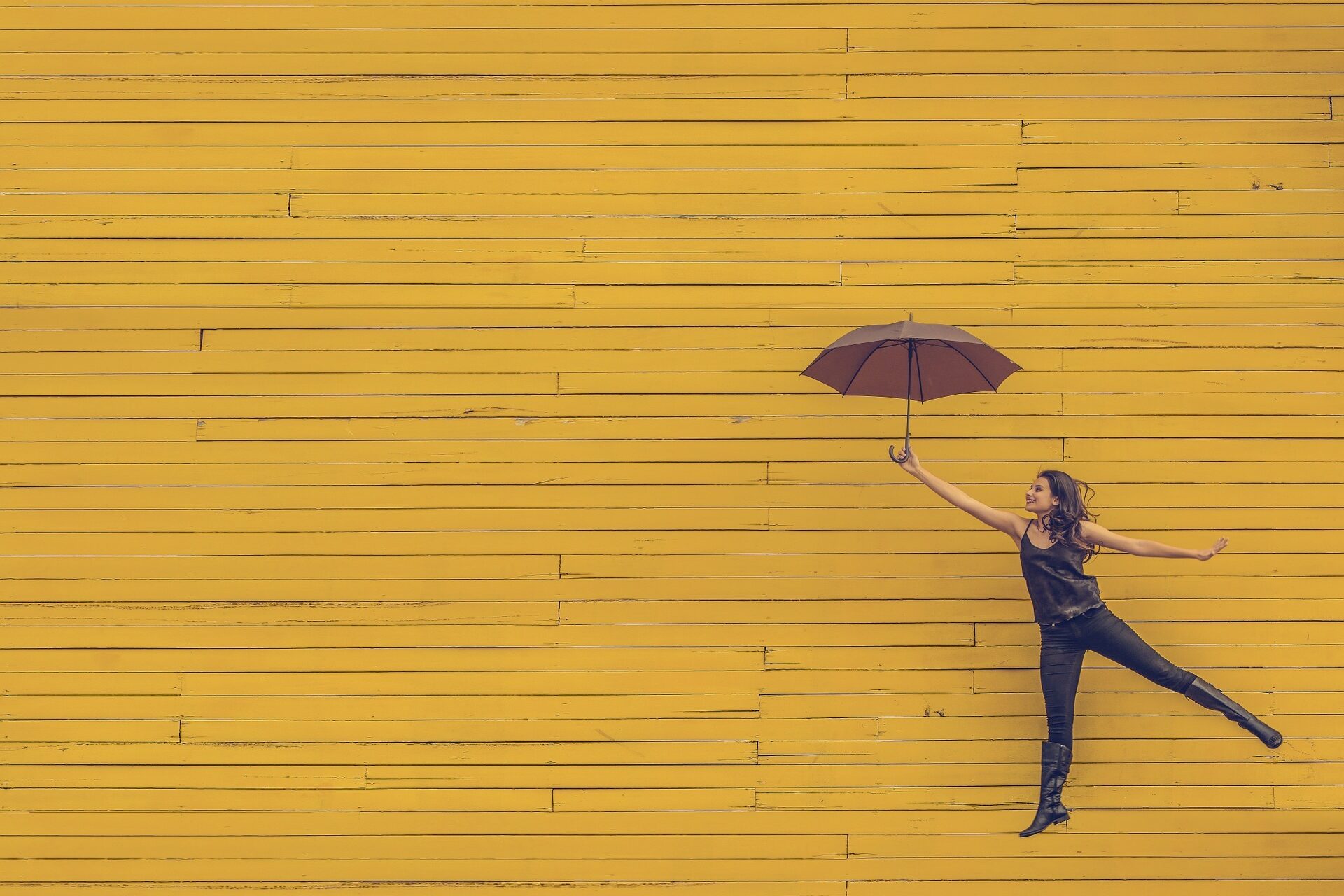 Bild einer Frau, die fröhlich mit einem Regenschirm in die Luft springt zur Veranschaulichung des Themas "Nicht für die Schule, sondern für das Leben lernen wir."