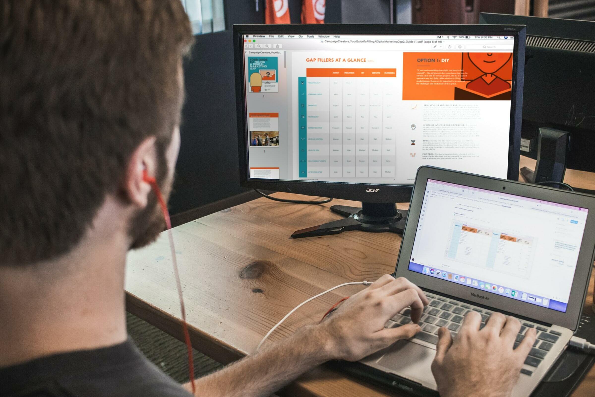 junger Mann vor einem Laptop sitzend mit weiterem Bildschirm