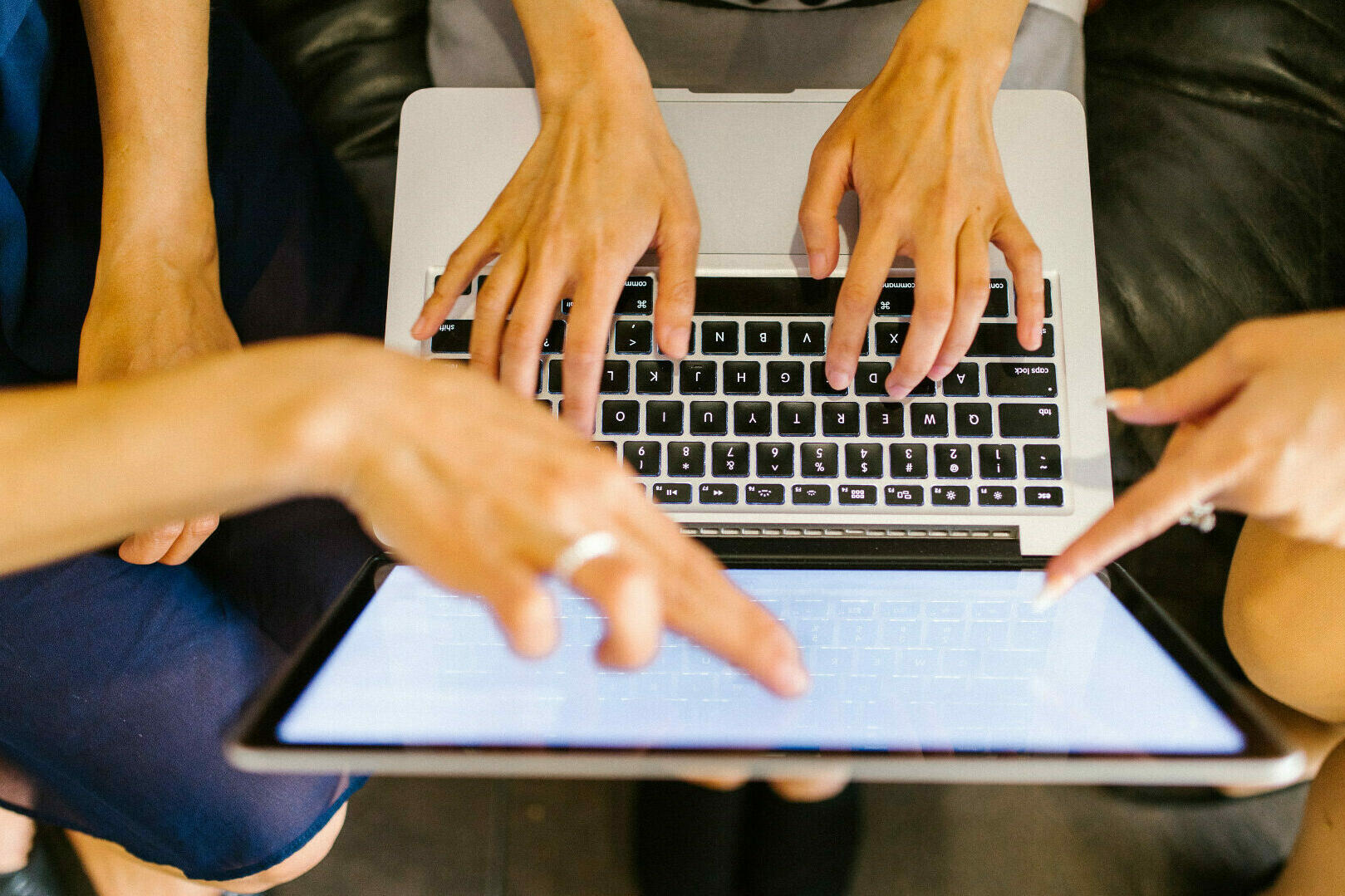 Mehrere Personen, die mit den Händen auf den Monitor eines Laptops zeigen.